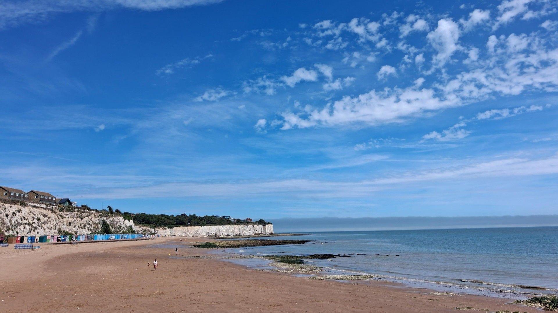Wispy cloud and blue skies over a calm coastline