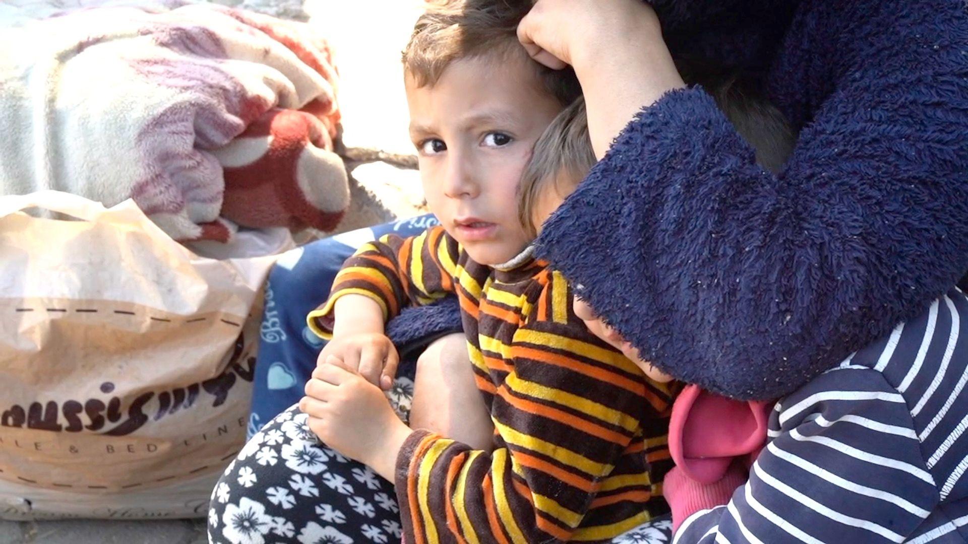 A boy looks frightened while a woman crouches by him