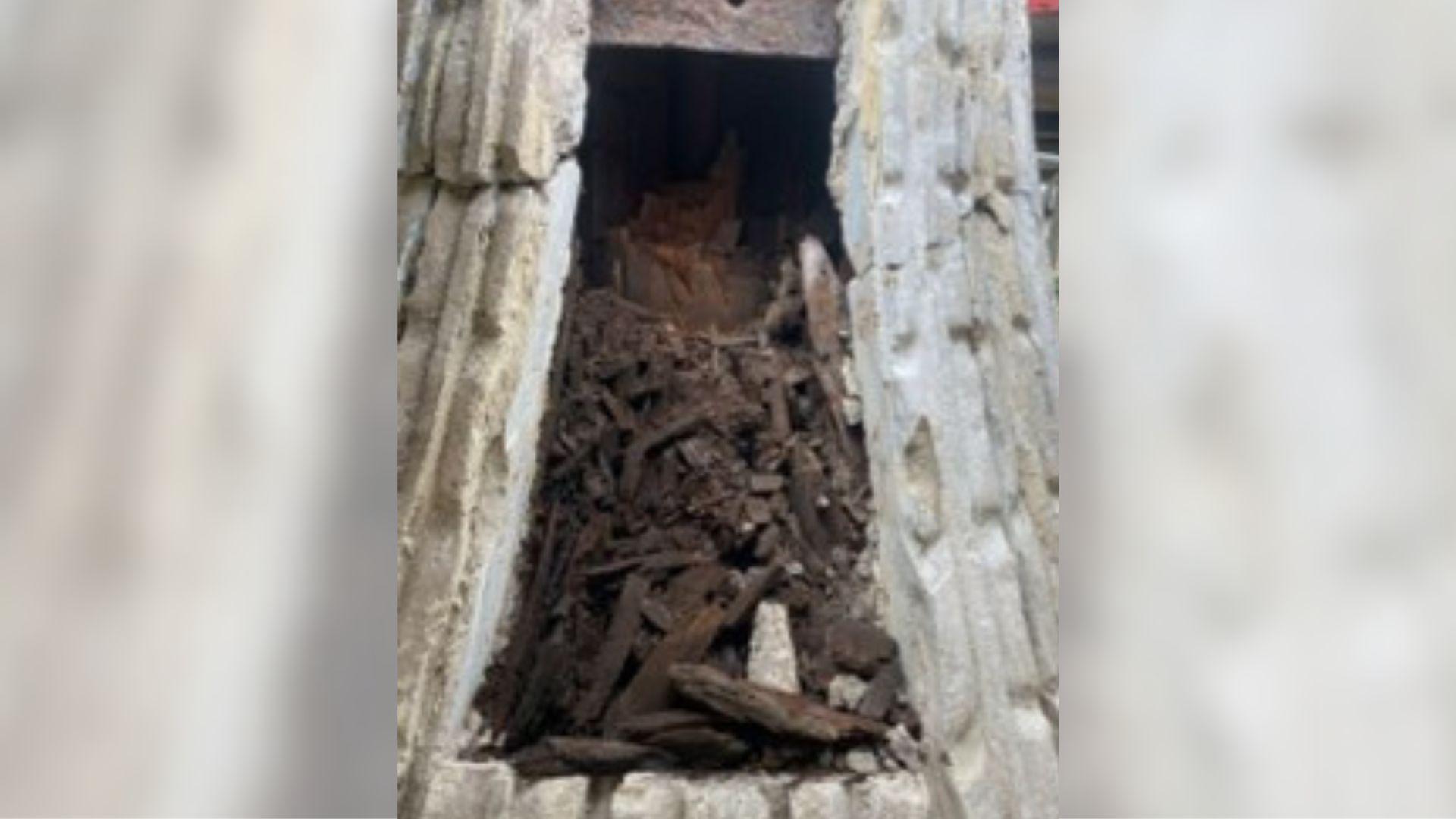 Piles of rotten wood seen inside a grey stone structure