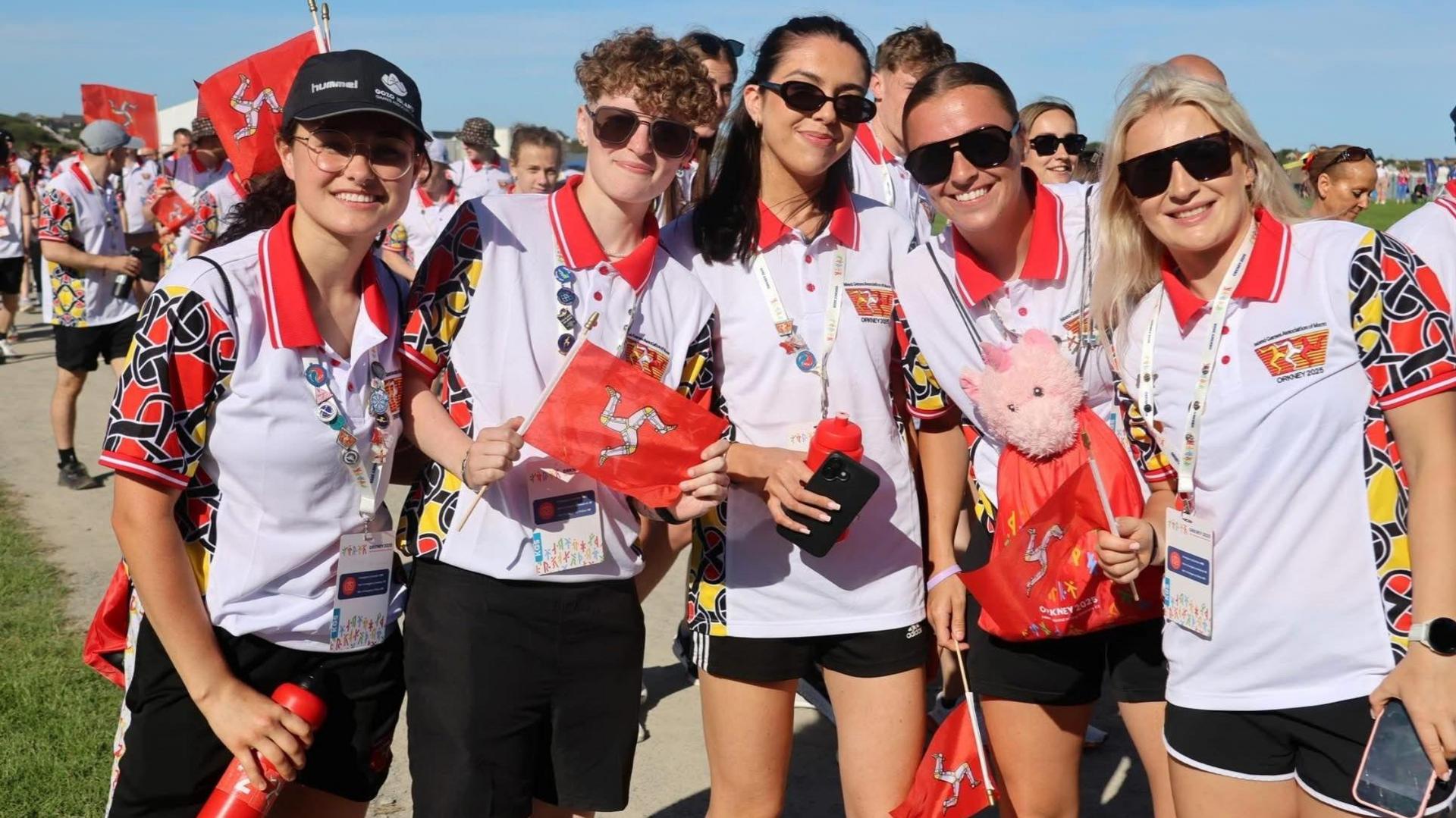 Members of Team Isle of Man holding small Manx flags, smiling.