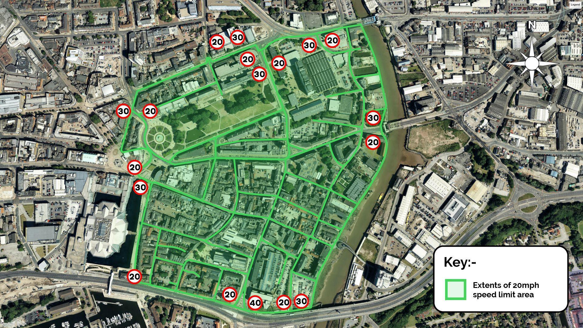 A satellite image showing a city centre, with a river running down the centre. A large part of the photo is shaded green to highlight a 20mph zone, with affected roads marked out in a darker shade of green. Small icons, designed to look like road signs, show where the "20", "30" and "40" zones begin and end.