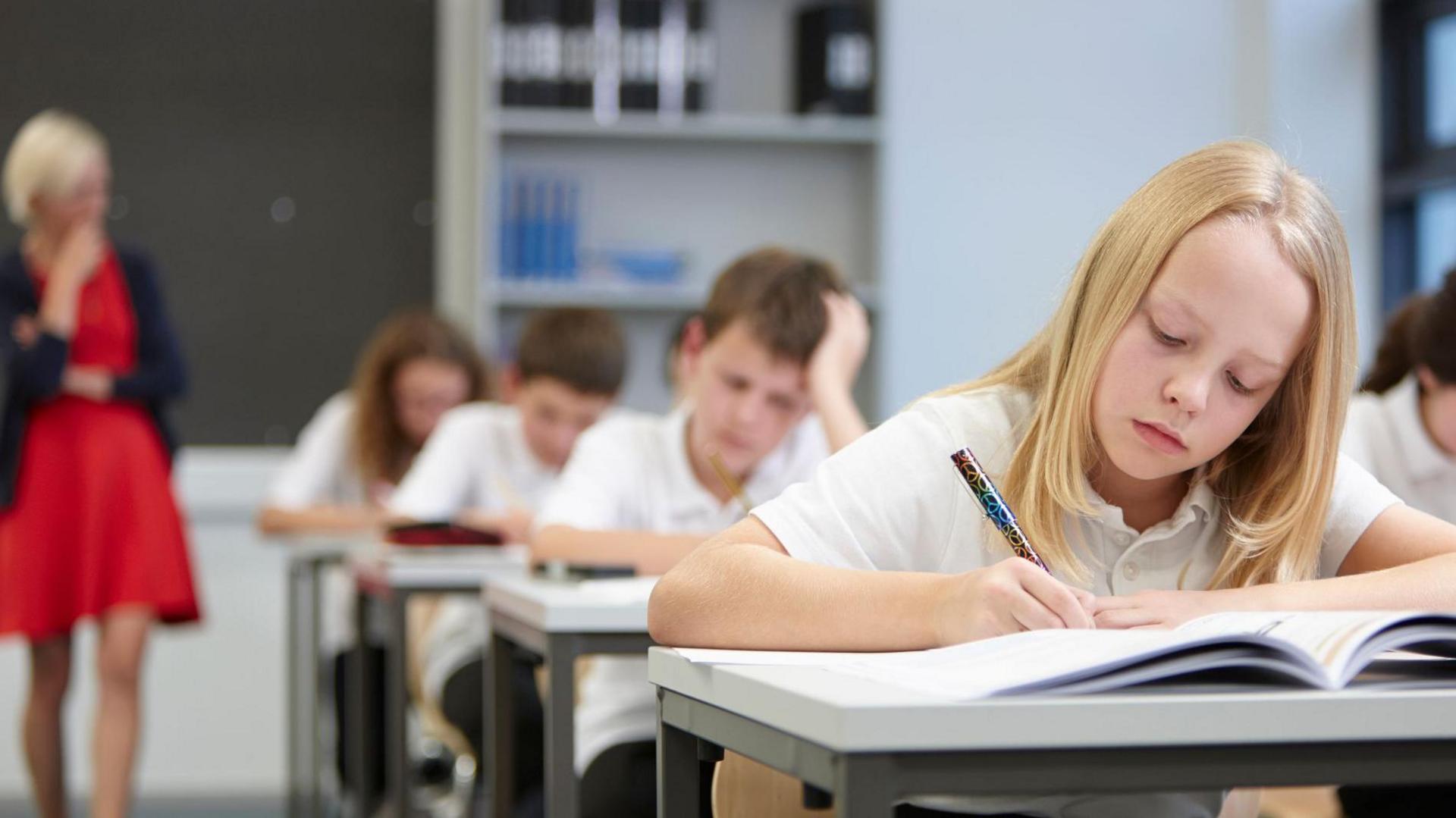 Female teacher watching class doing  exam - stock photo