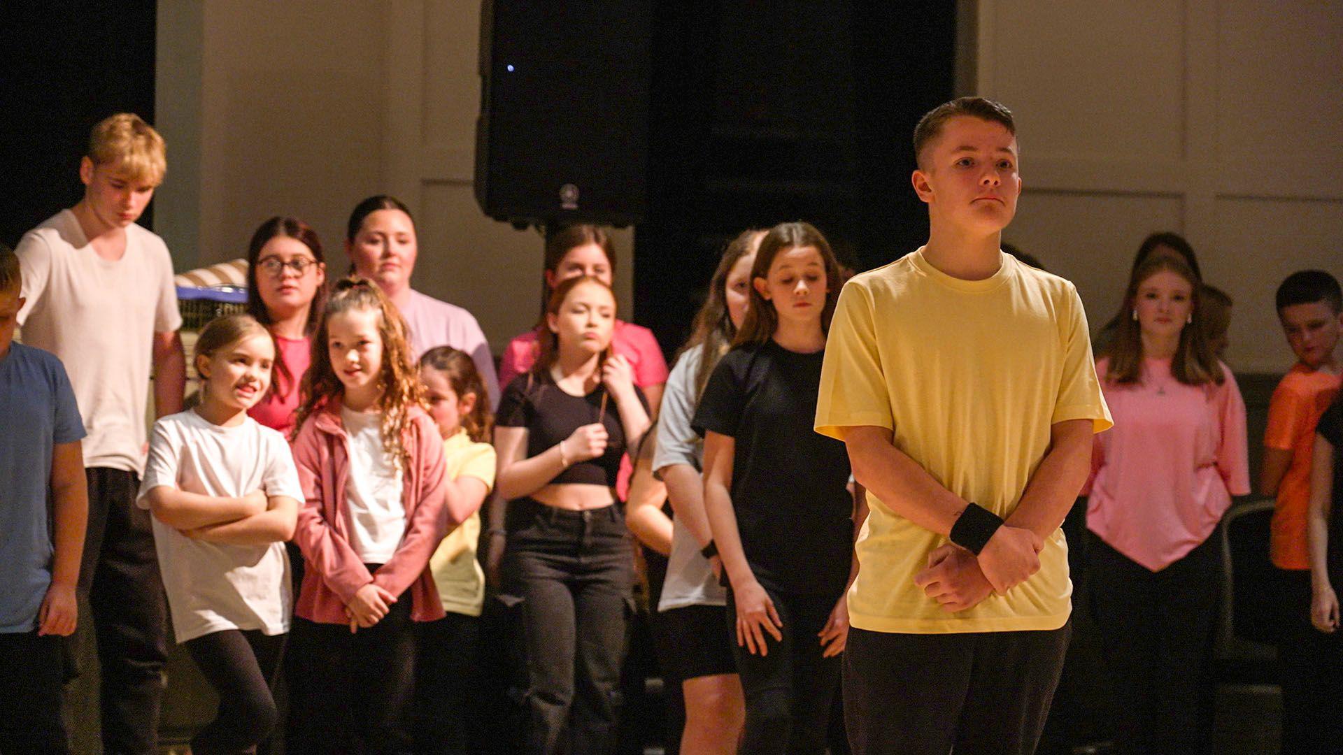 A group of children ready to perform, standing inside the Newbridge Memo