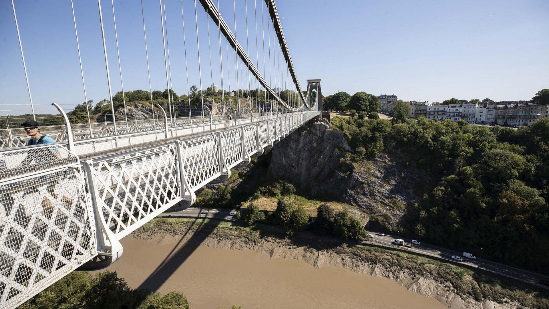 The Clifton Suspension Bridge seen from the Clifton side looking towards Leigh Woods. There are people on the bridge and the River Avon is visible below