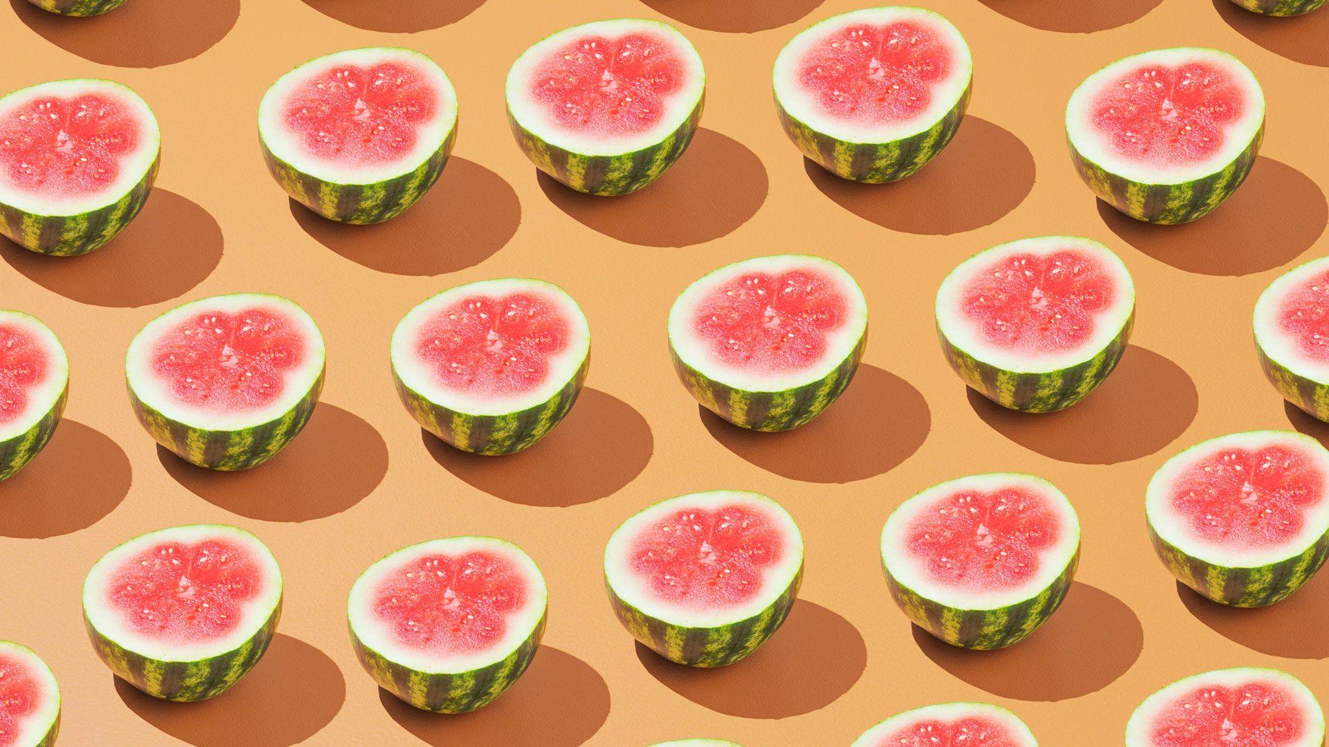 Rows of halved watermelons on a pale orange background