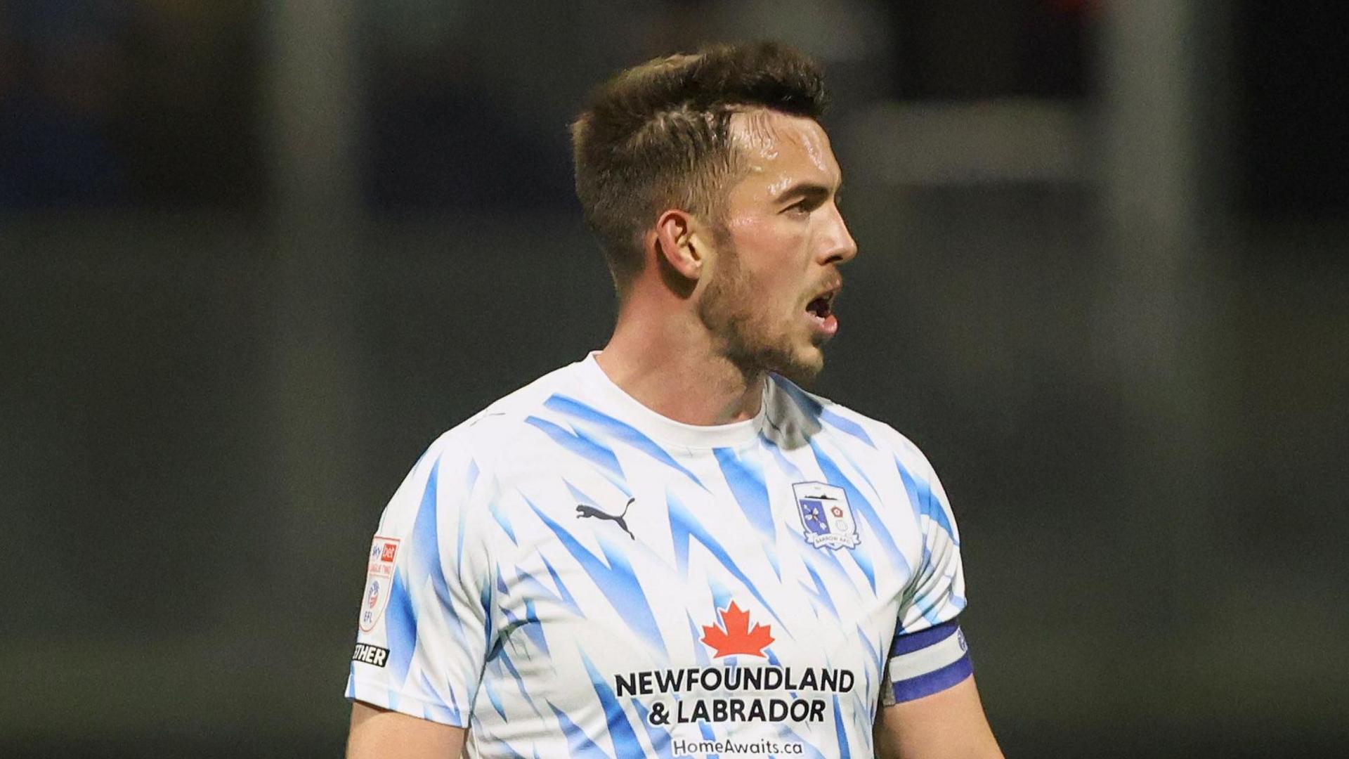 Niall Canavan playing for Barrow with his head looking to the right of the image