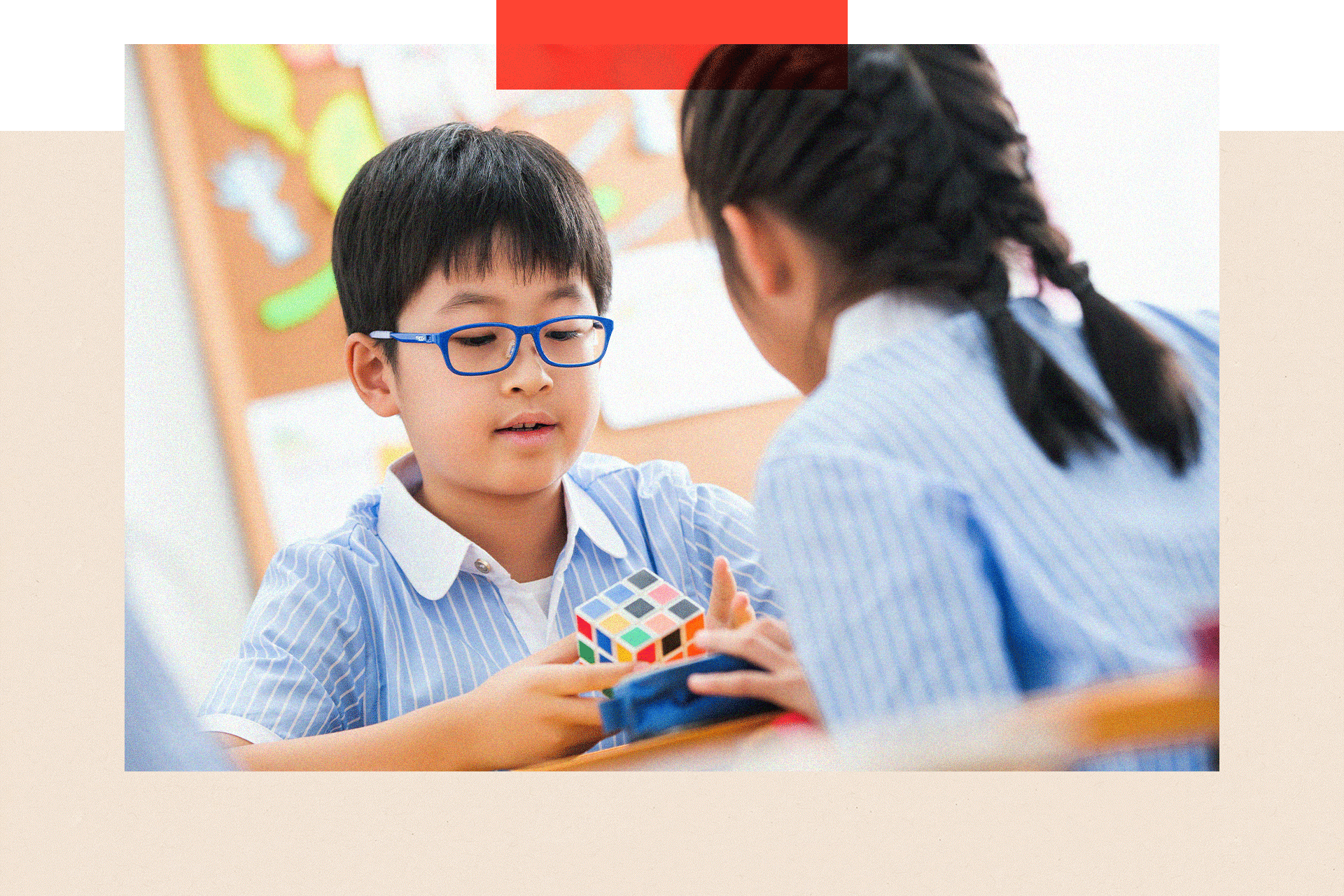 Two children in school uniform play with a colourful puzzle cube