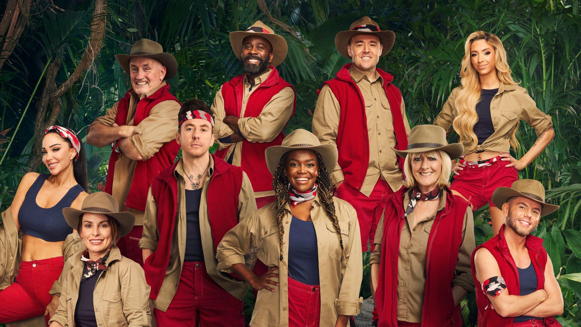 The cast of I'm a Celebrity 2024 pose together wearing their jungle outfits against a jungle backdrop full of plants