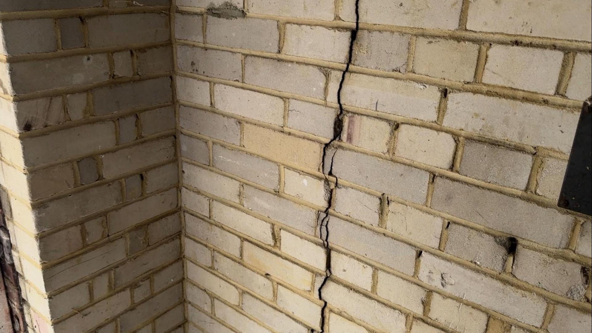 Picture shows a large crack in the wall of a garage at the block. A crack is clearly visible in the grey brickwork.