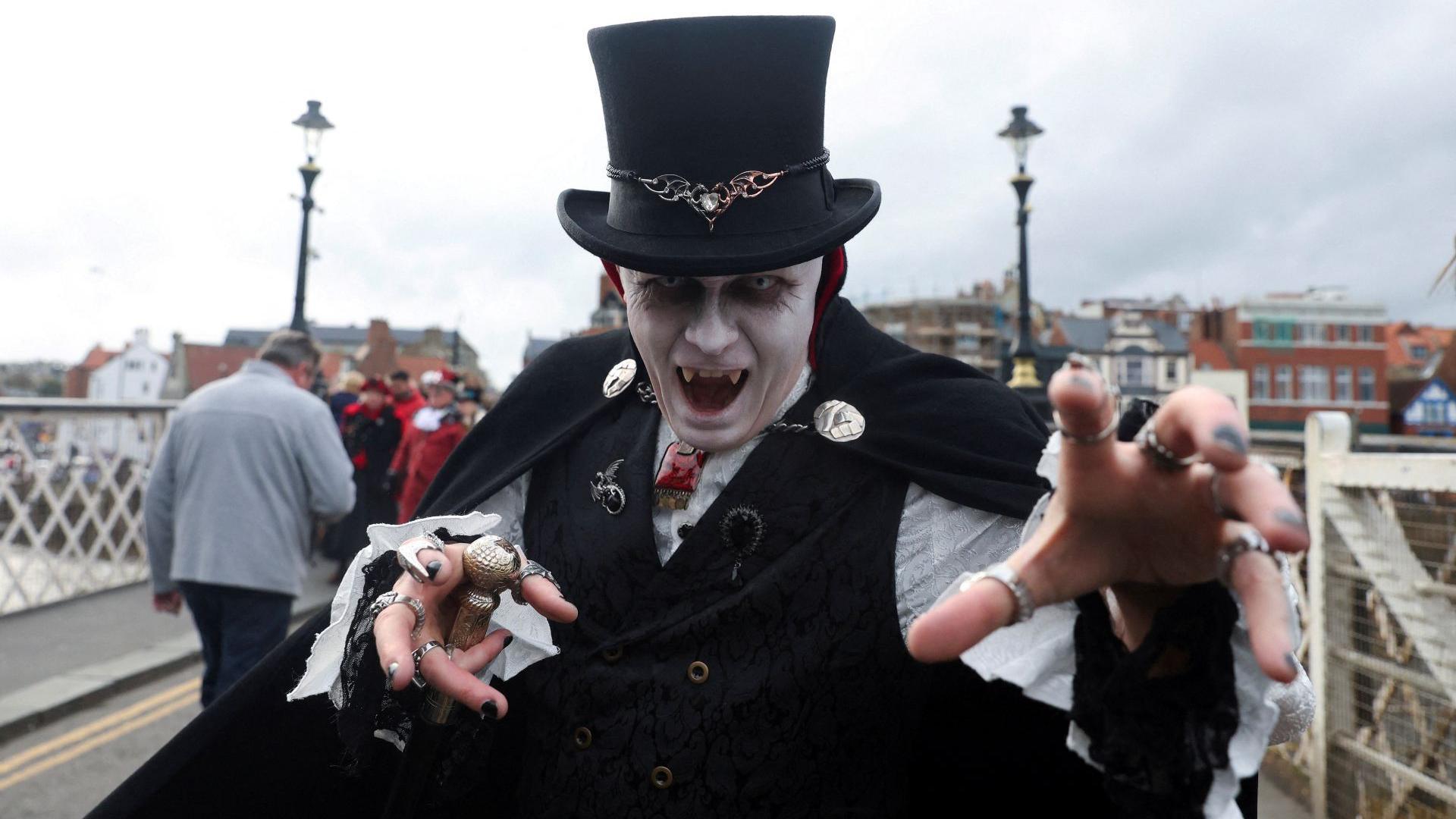 A man wearing a costume poses for a photograph on Halloween during Whitby Goth Weekend in Whitby