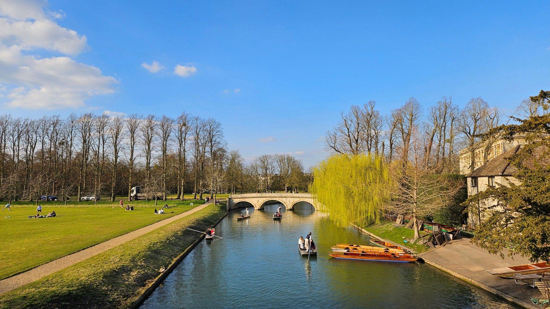 Punters on a river on a sunny day in Cambridge.