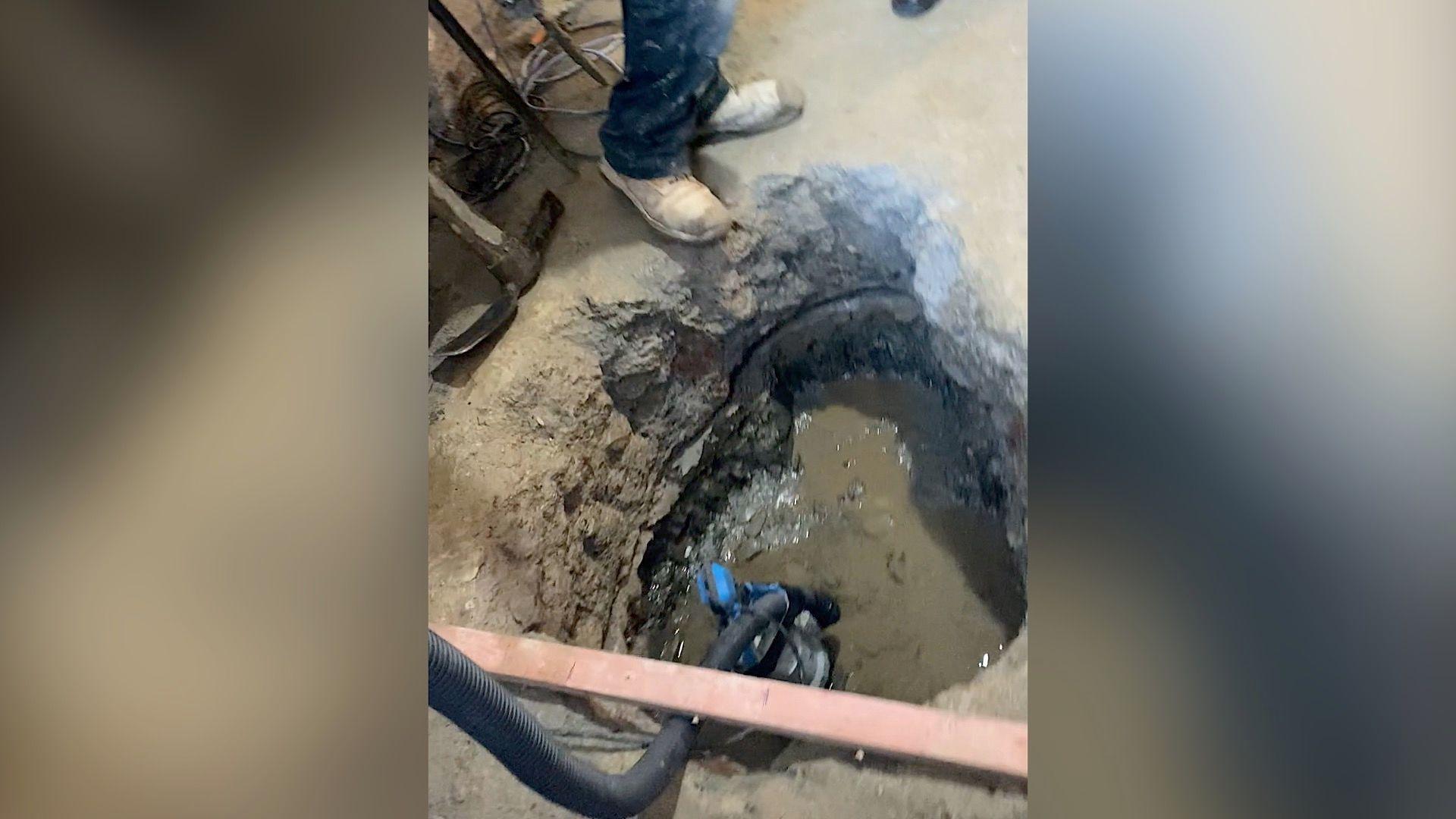 Hole in concrete floor with water in the bottom and a pump taking water outside