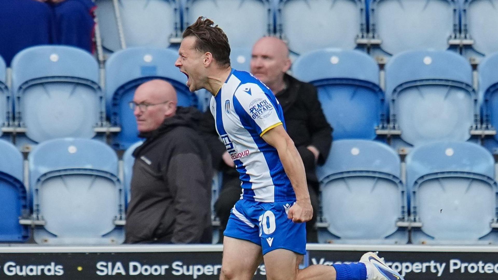 Jack Payne runs with his fist clenched and his mouth open in celebration at a goal