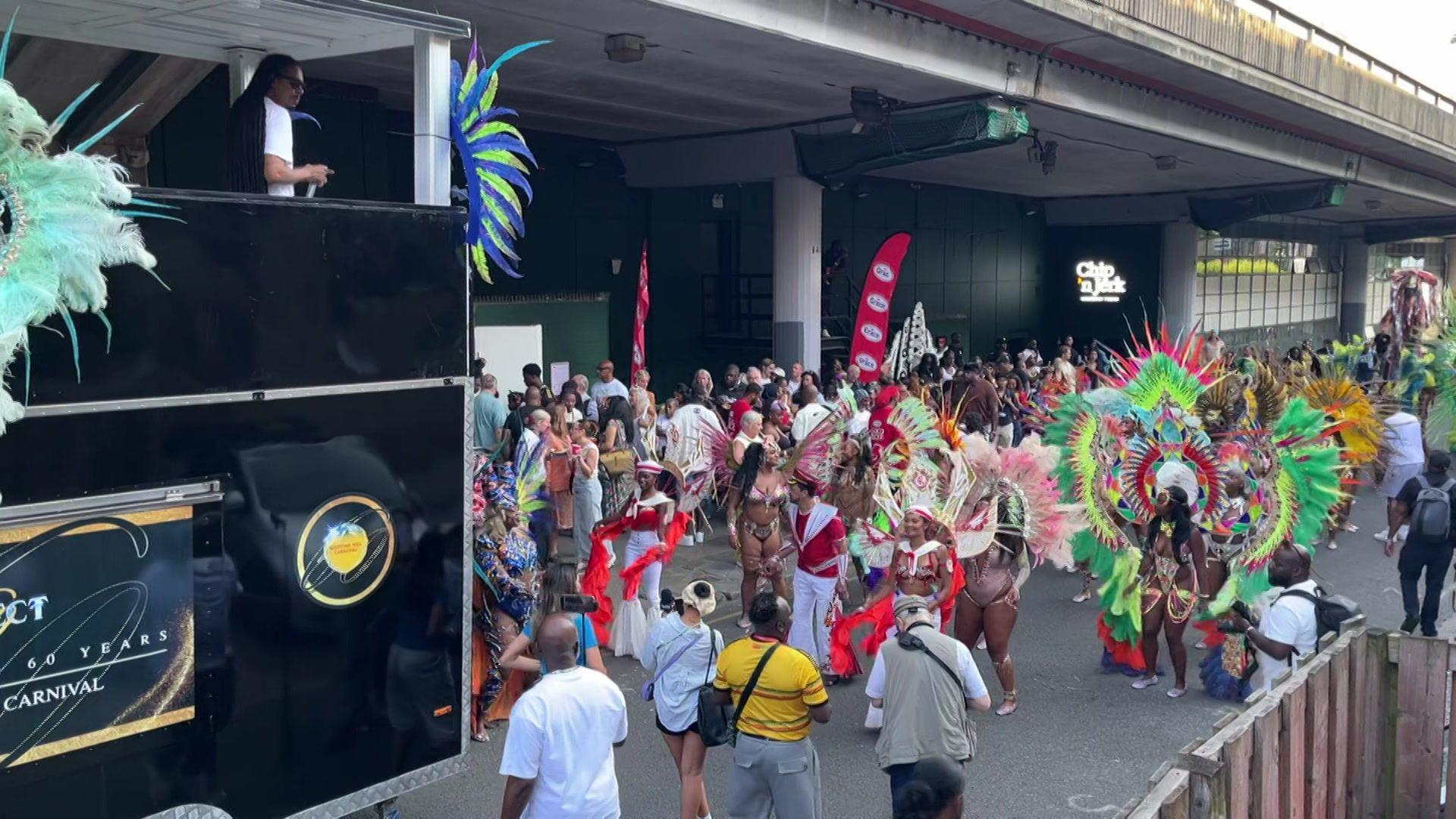 Colourfully dressed masqueraders gather beside a sound system truck during the launch event of Notting Hill Carnival.