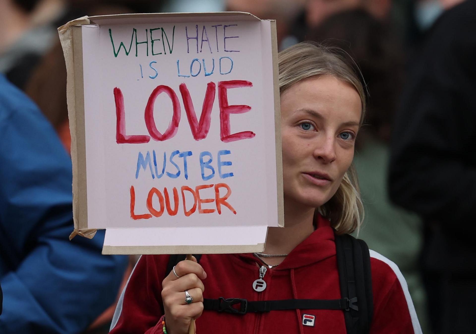 An anti-racist protester holds a sign as they gather in Brentford, west London