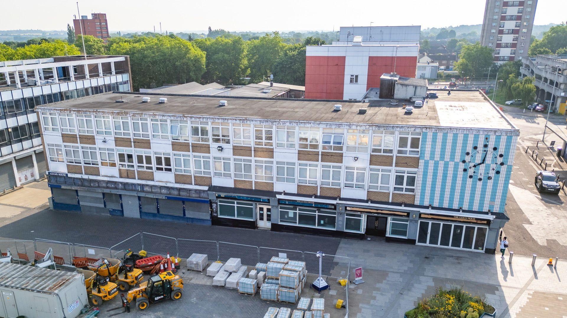 An aerial view of Market Square in Harlow, showing a concrete building with construction materials being set up in front of it.
