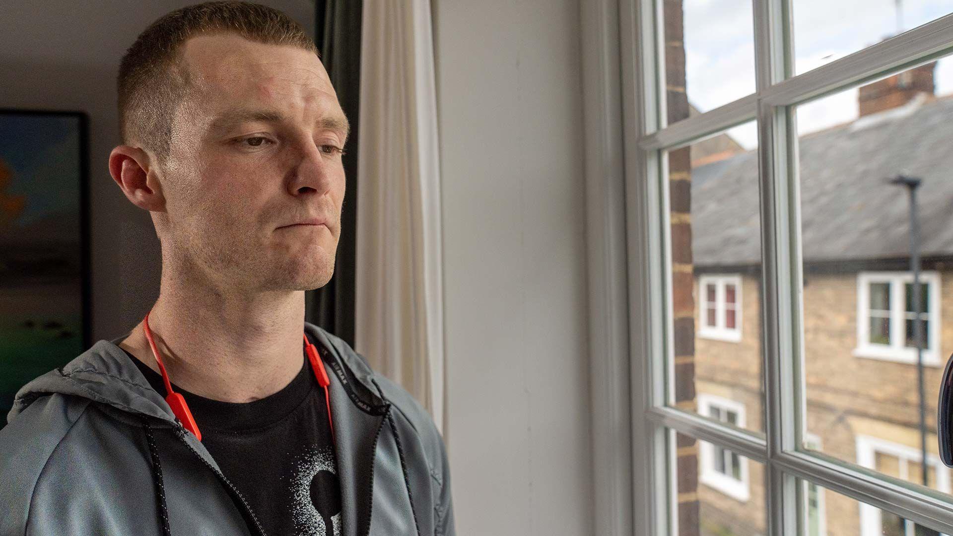 Jamie stands next to a window