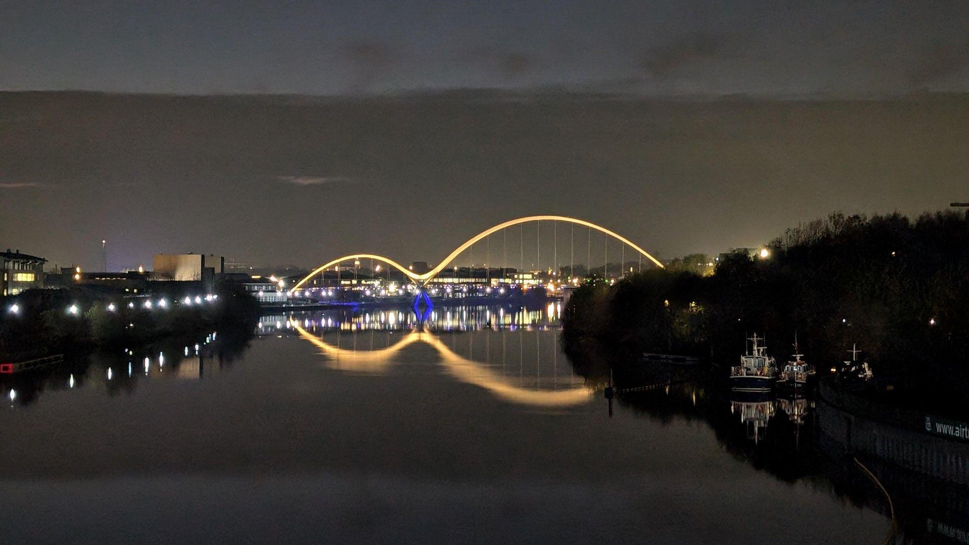 A bridge with two brightly lit arches at night time