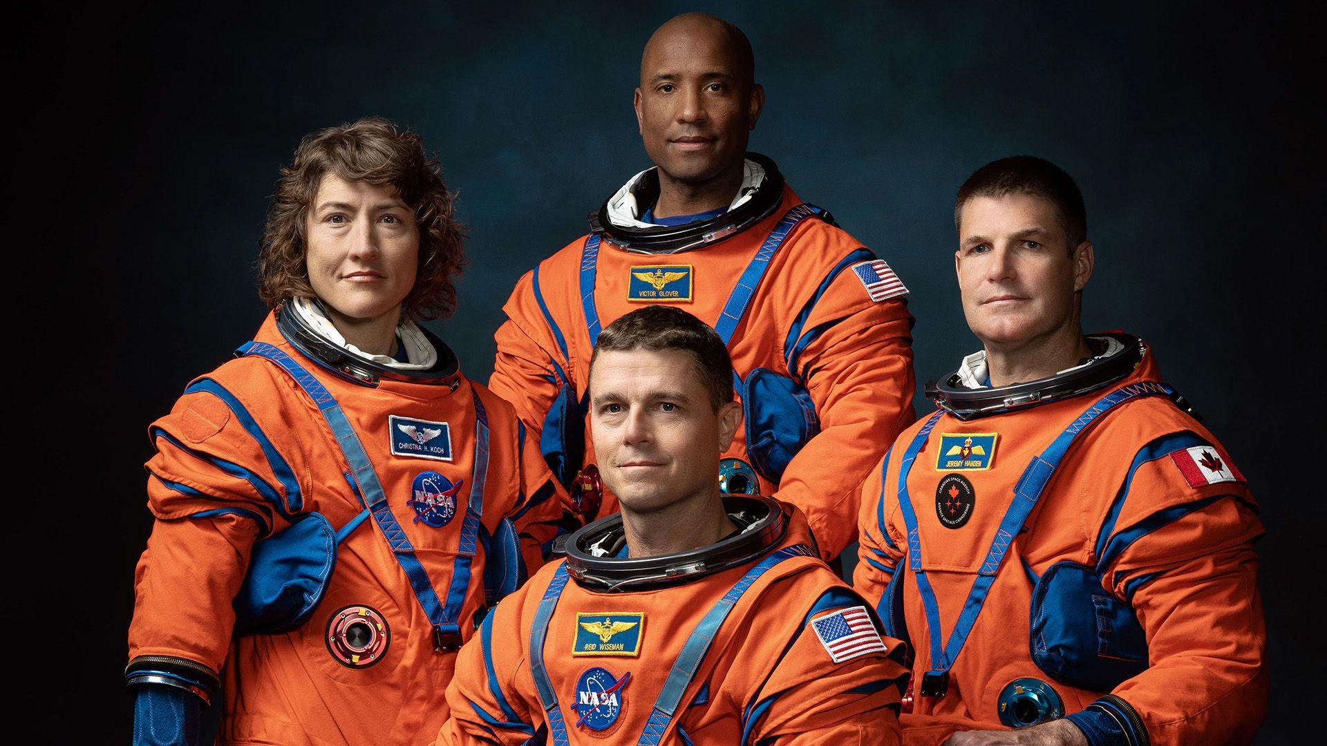 Christina Koch, Reid Wiseman, Victor Glover and Jeremy Hansen wear orange space suits and pose as a group