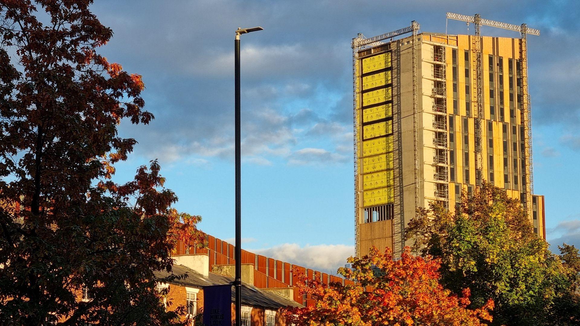 Broadcasting Tower stands above trees against a cloudy sky.