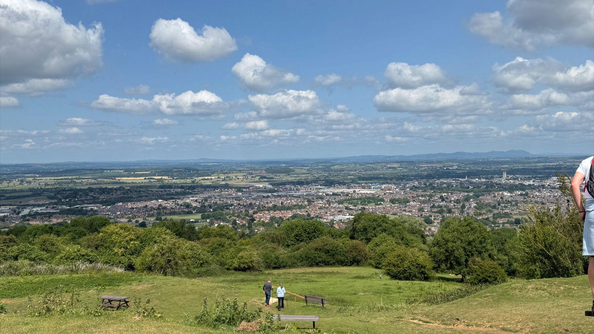 A shot of Gloucester from the top of Robinswood Hill with some people admiring the view.