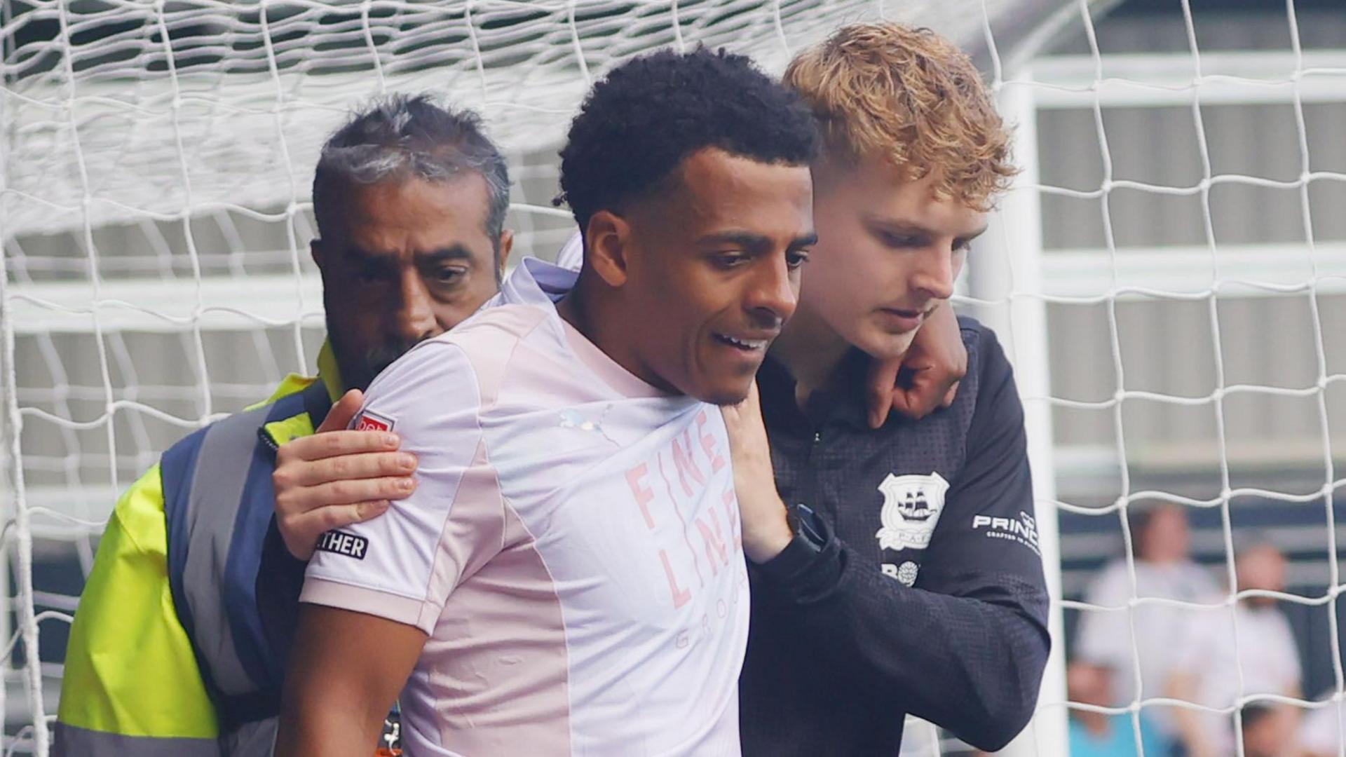 Caleb Watts is helped from the field after being injured at Luton