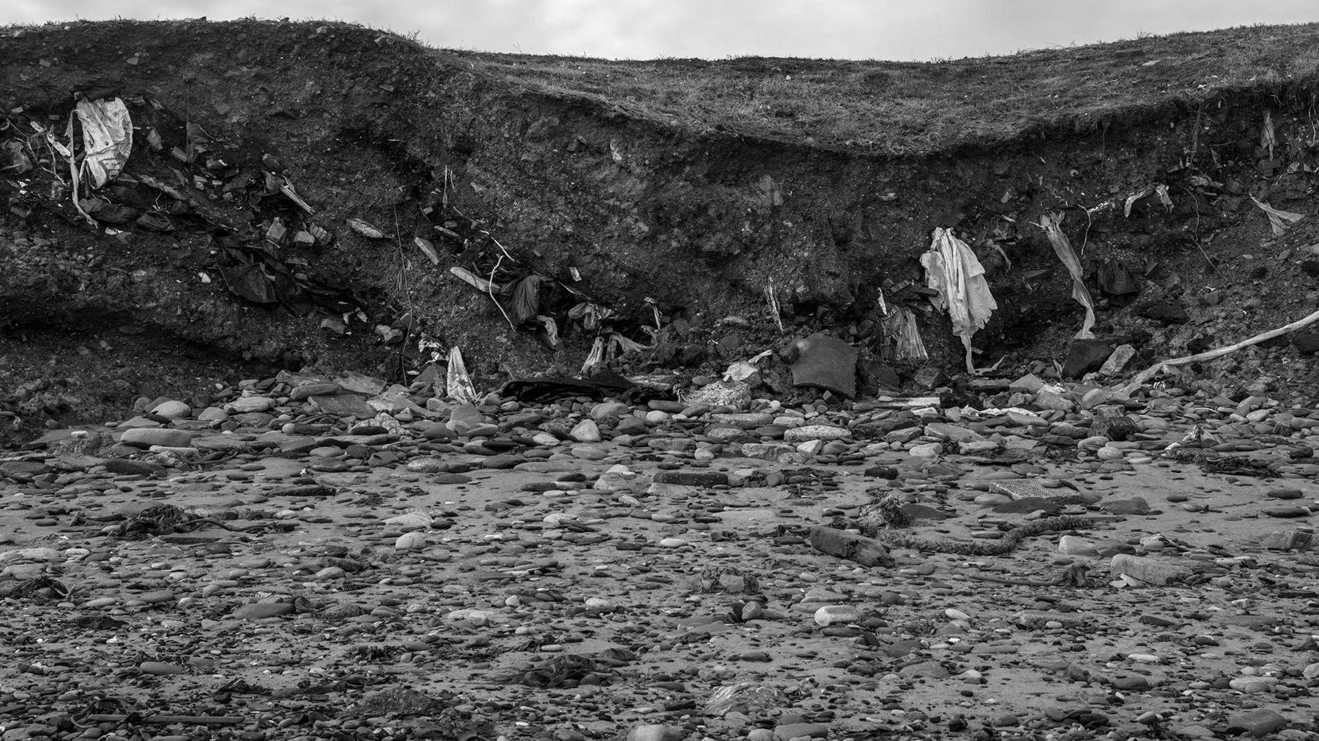 A line of debris in a cliff face extending out onto the beach 