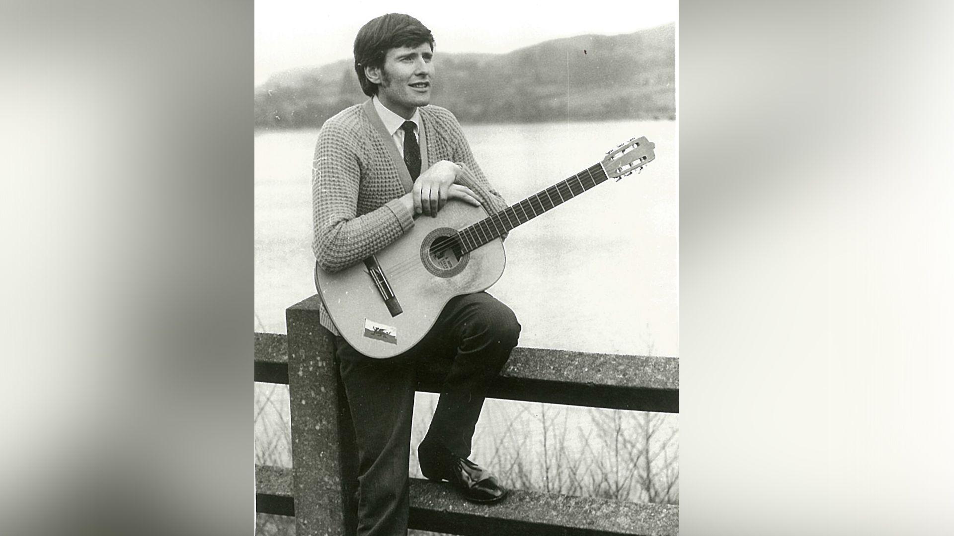 Edward Morus Jones gyda'i gitar ar lan y llyn