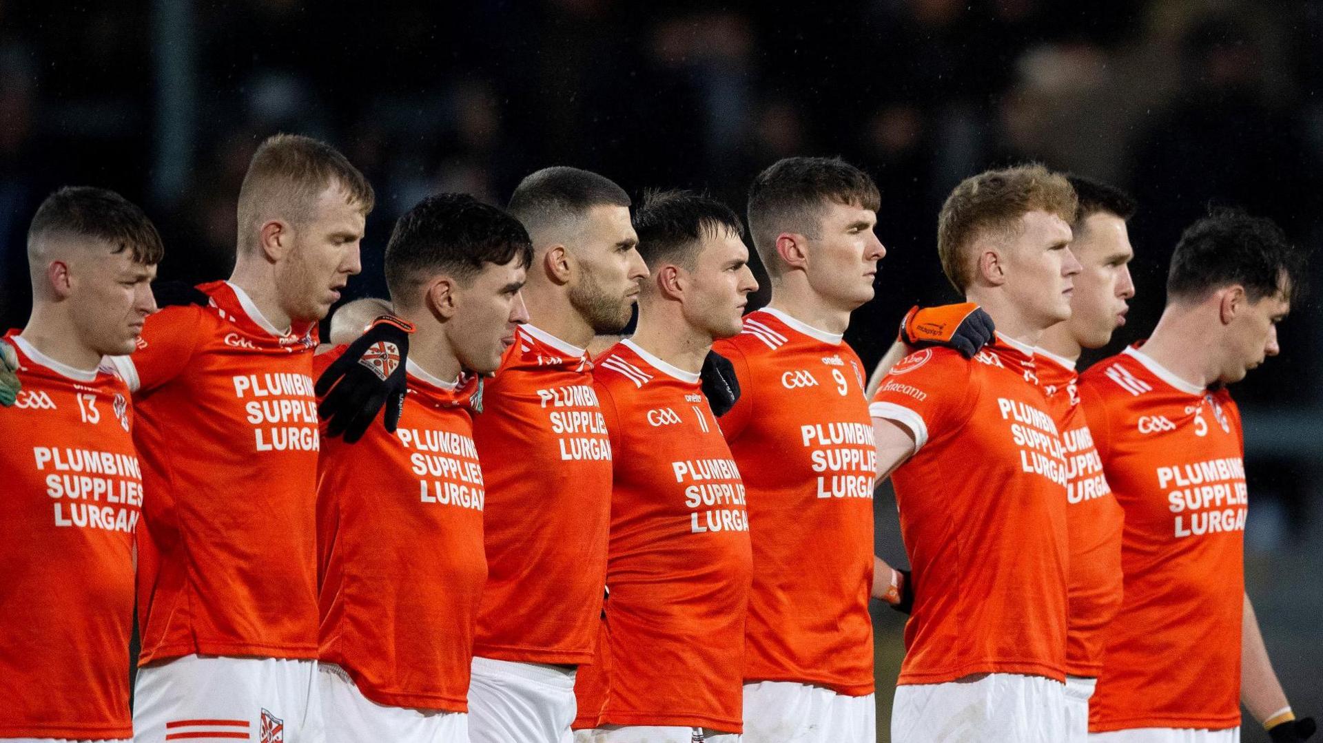 The Clann Eireann players stand for the Irish national anthem at the Athletic Grounds