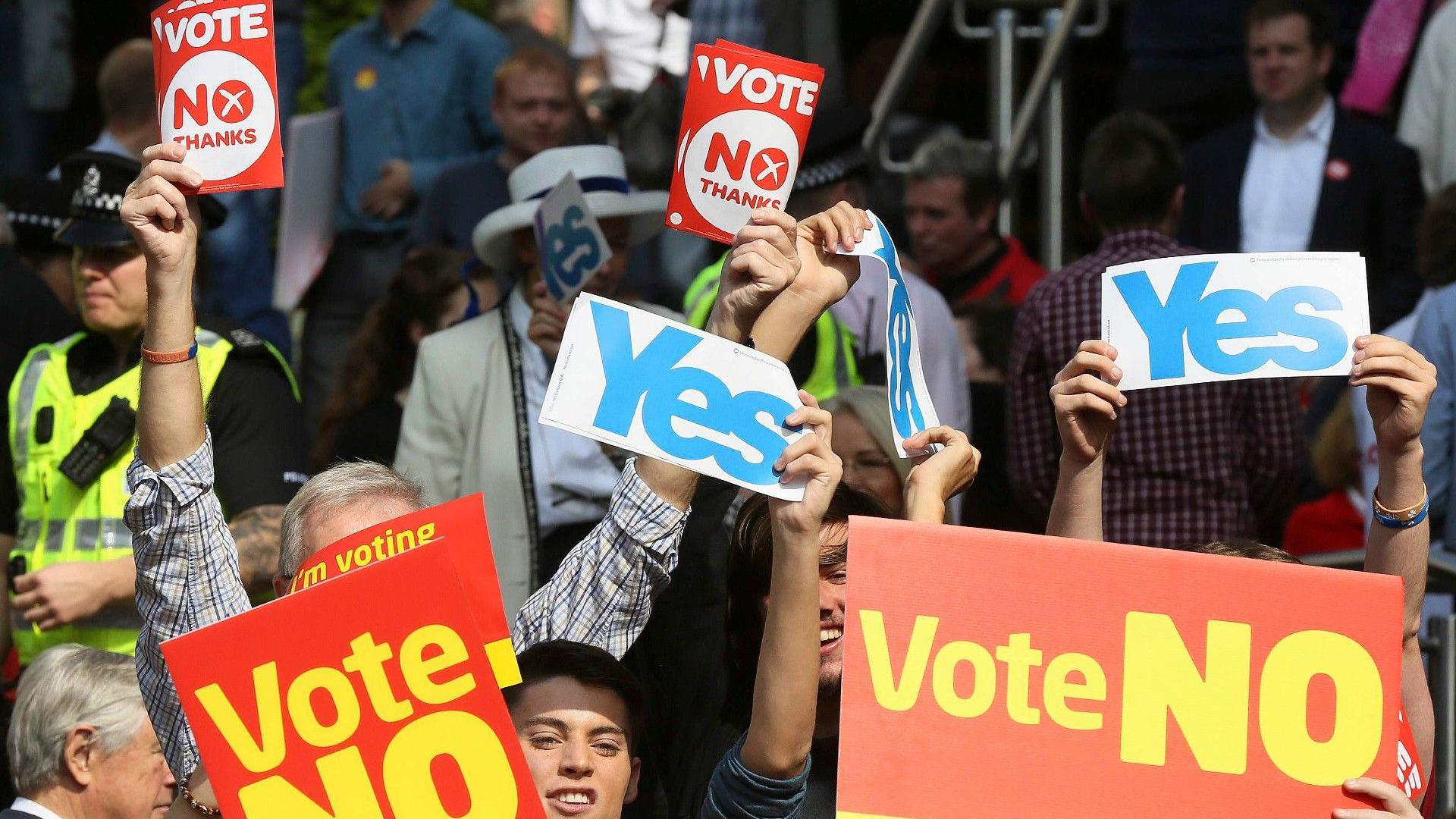 A group of people holding signs saying Yes and Vote No during the referendum campaign.