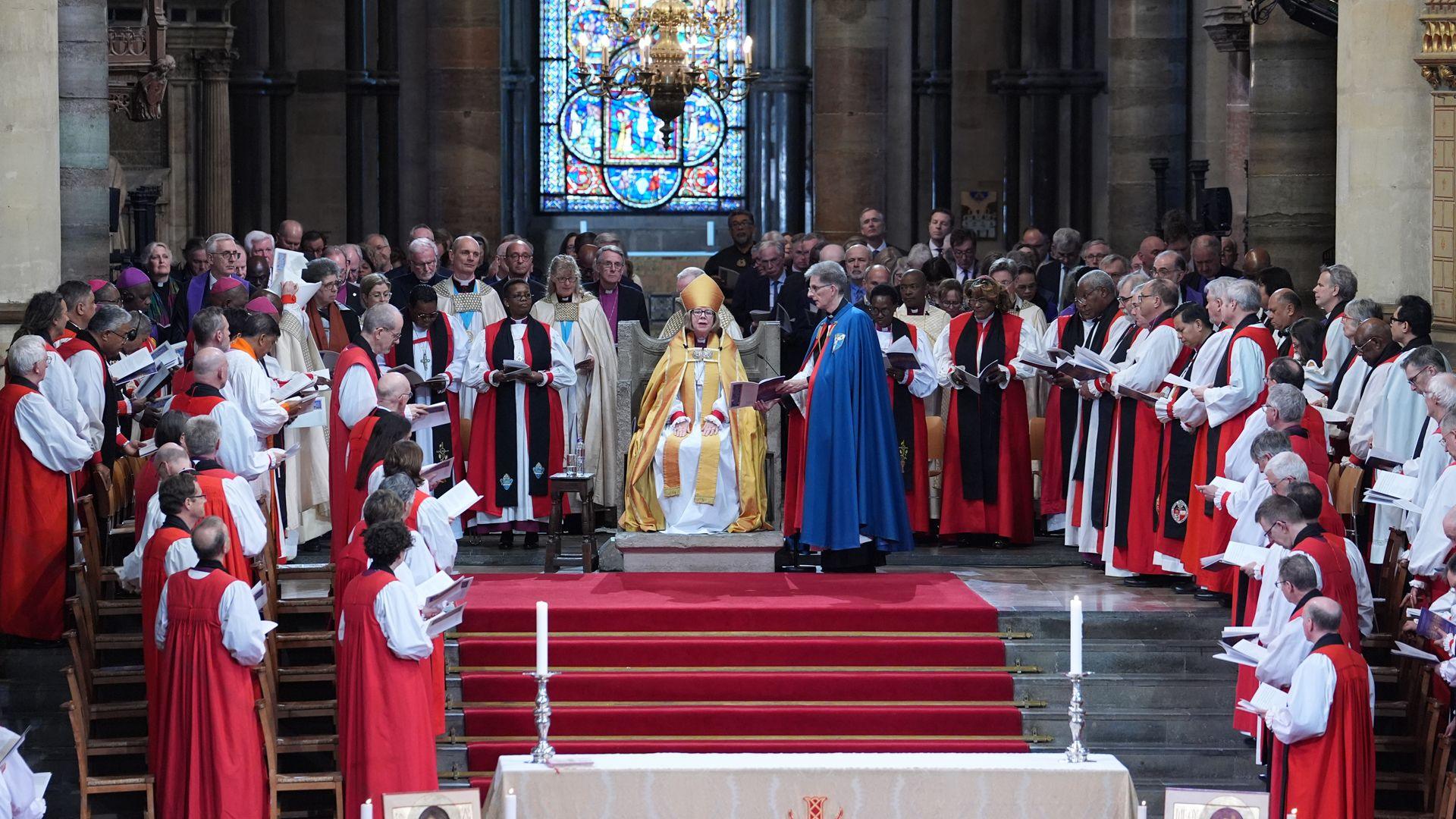 Dame sarah on the throne with lots of people around her.