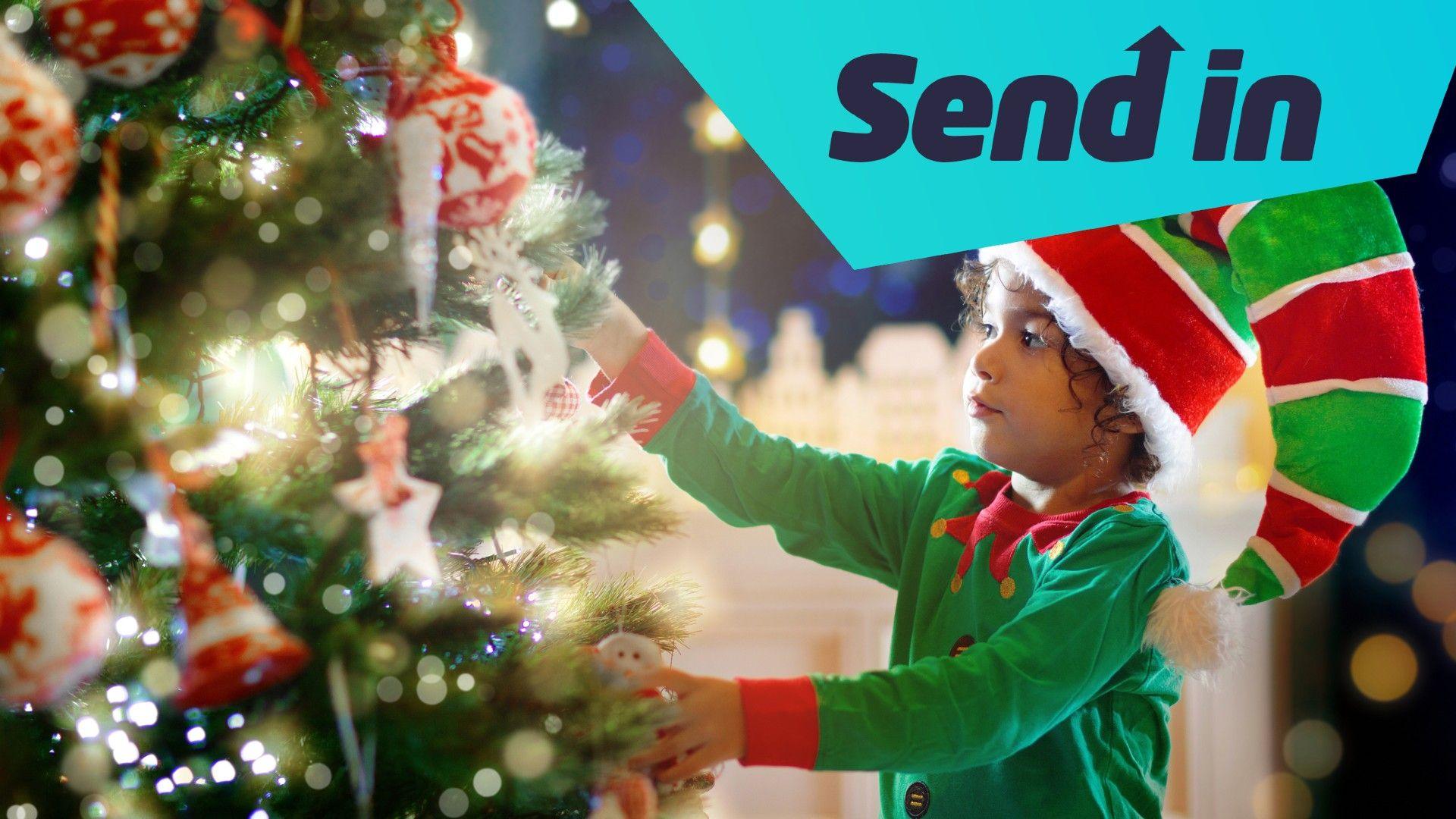 Boy dressed as elf putting decorations on Christmas tree. 