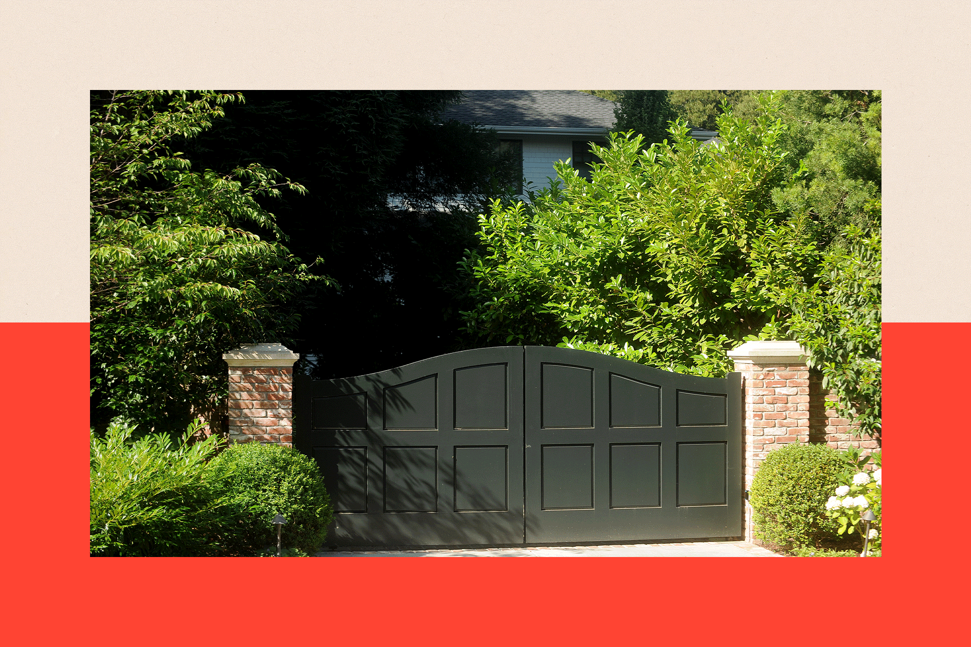 Large gate and green bushes with a house in shadows in the background