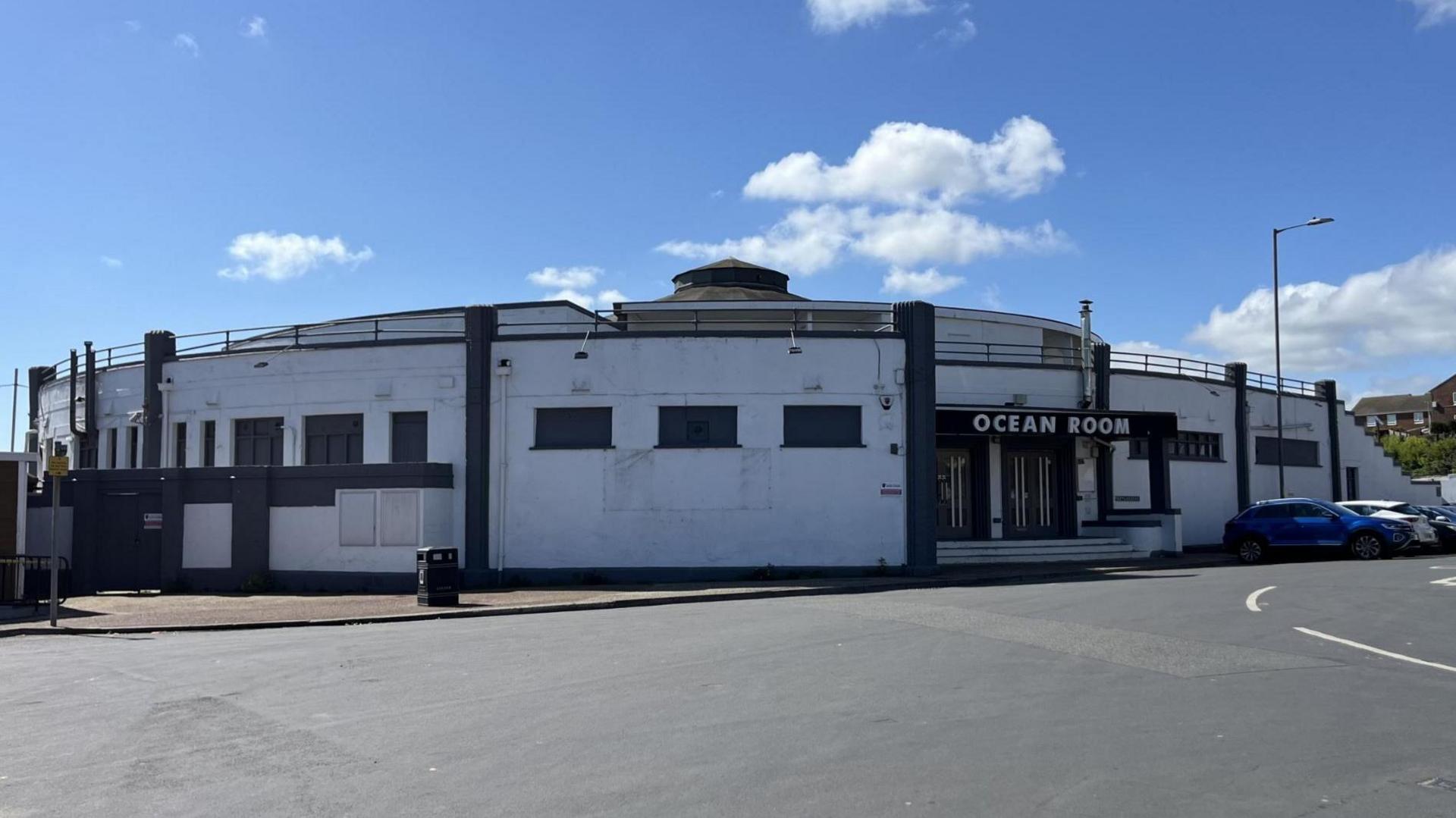 A white circular building low-level building with the words: Ocean Room above the doors.