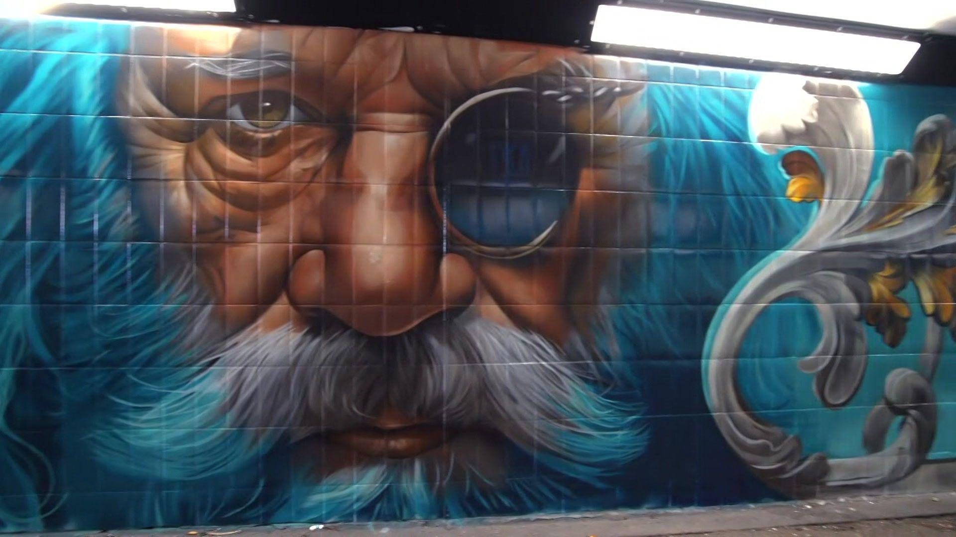 A painting of a bearded man wearing a monocle painted on the wall of a subway.