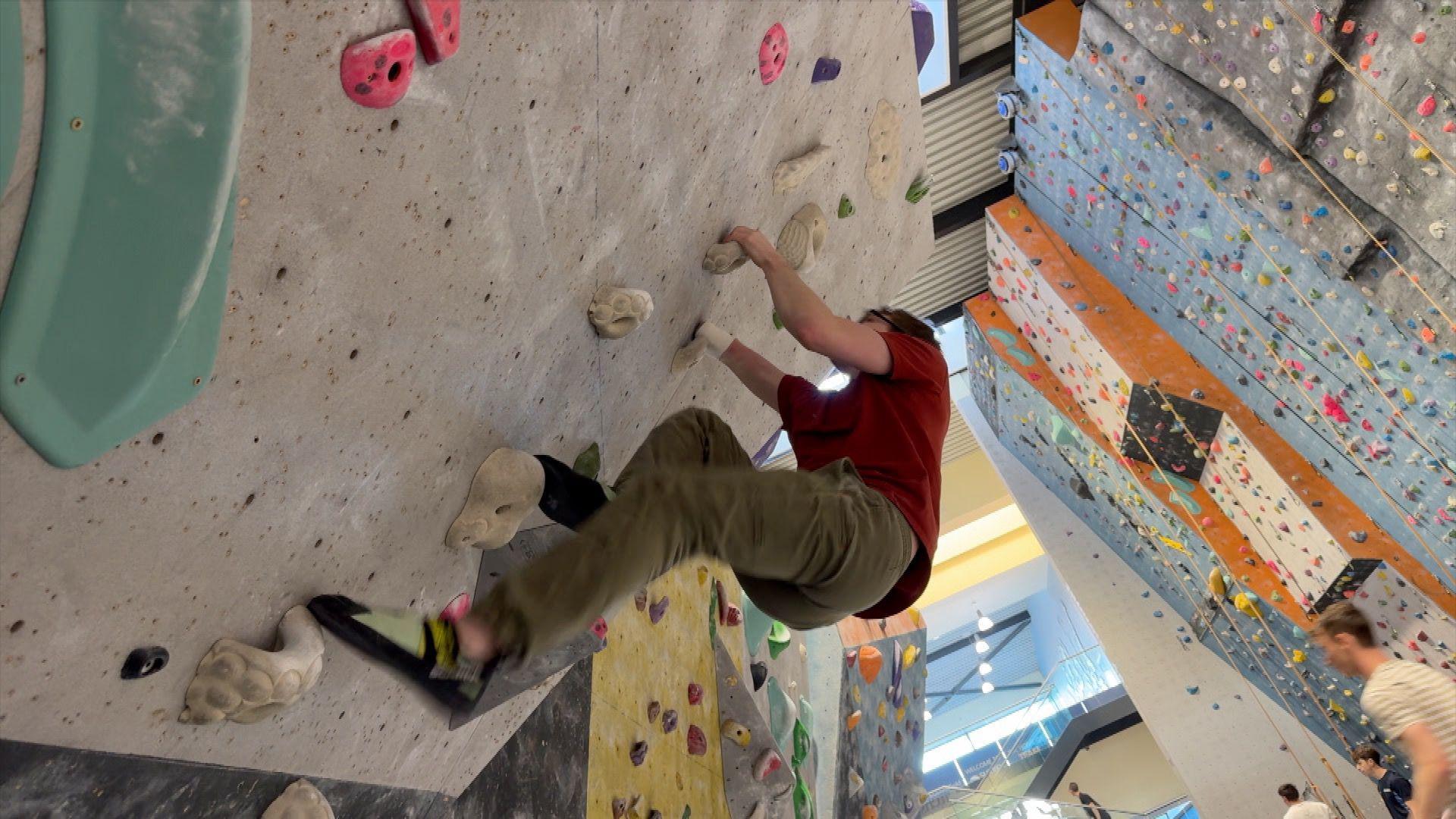 Matthew Phillips climbing up a wall in Surrey Summit climbing centre.