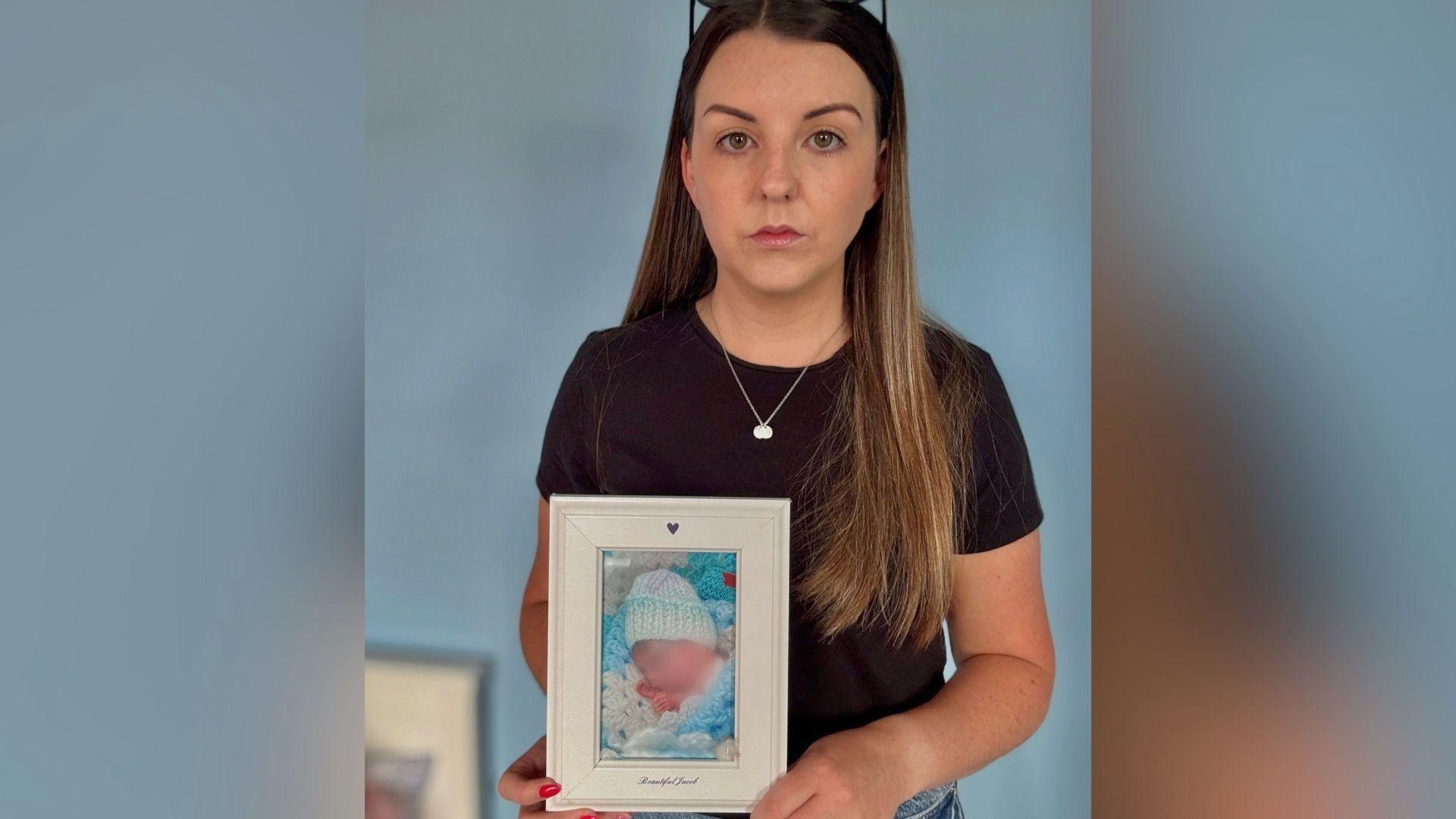 This has been pre blurred before being sent to the BBC. She shows a woman with long balayed hair, a silver necklace and a brown t-shirt. She looks straight into the camera  