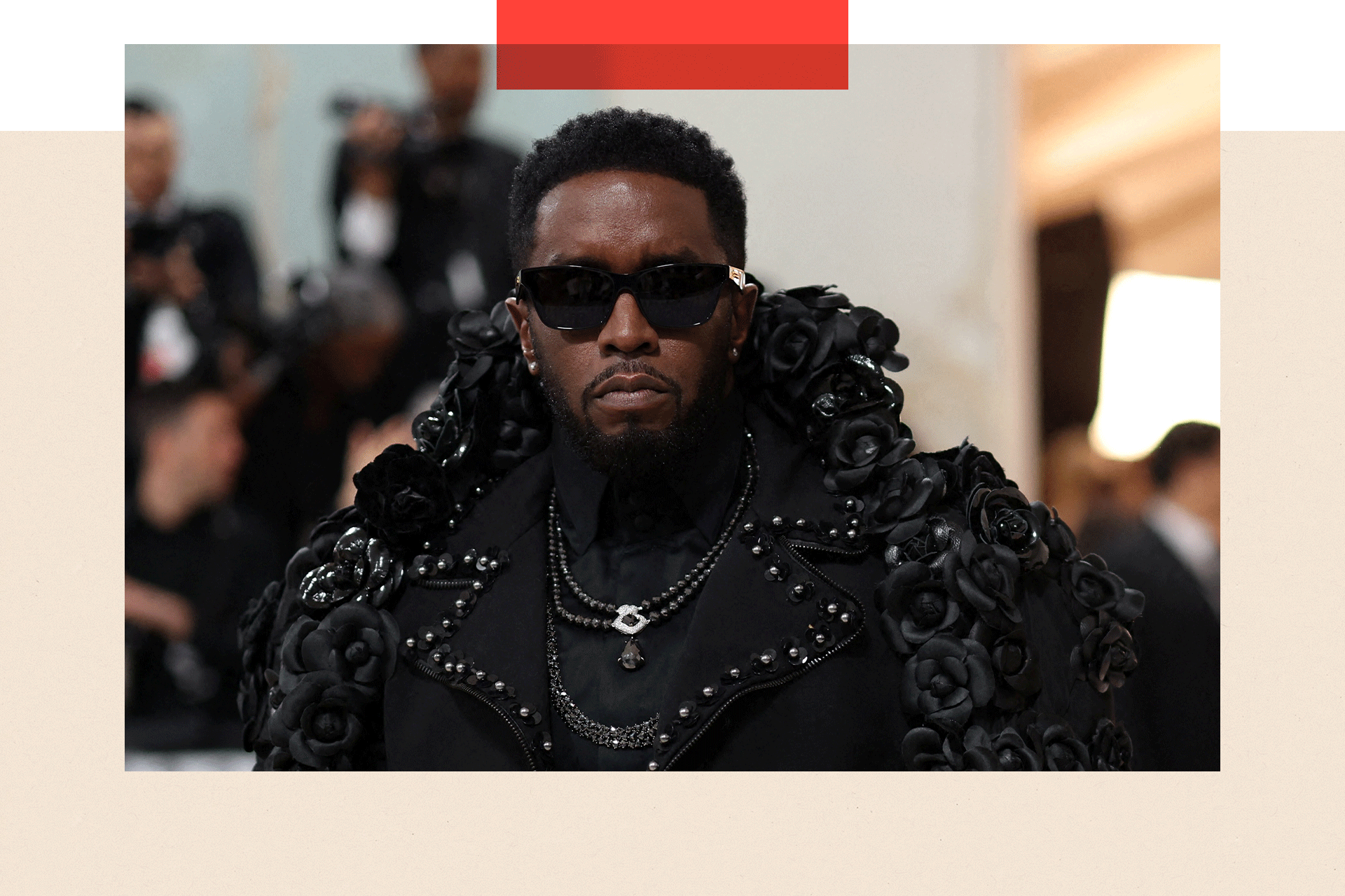 Diddy wears sunglasses, necklaces and a black top with wide collars