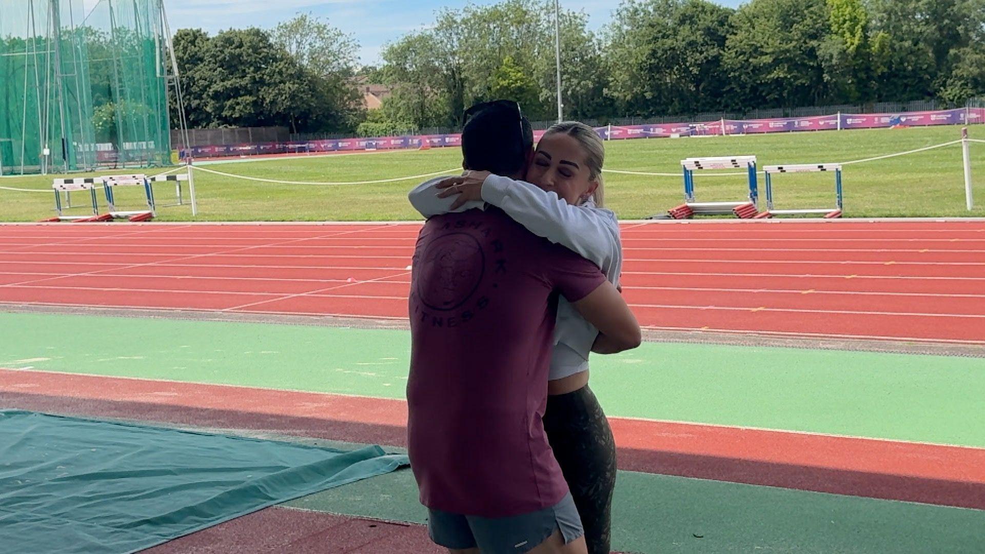 Mike Woodison and Ali Smith hugging at Loughborough athletics track.
