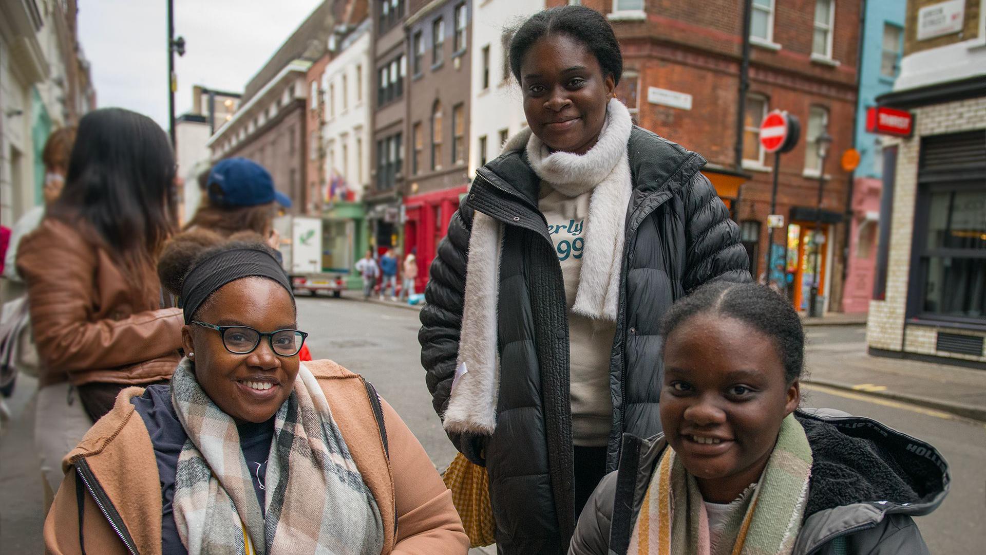 Three women wearing jackets look at the camera smiling