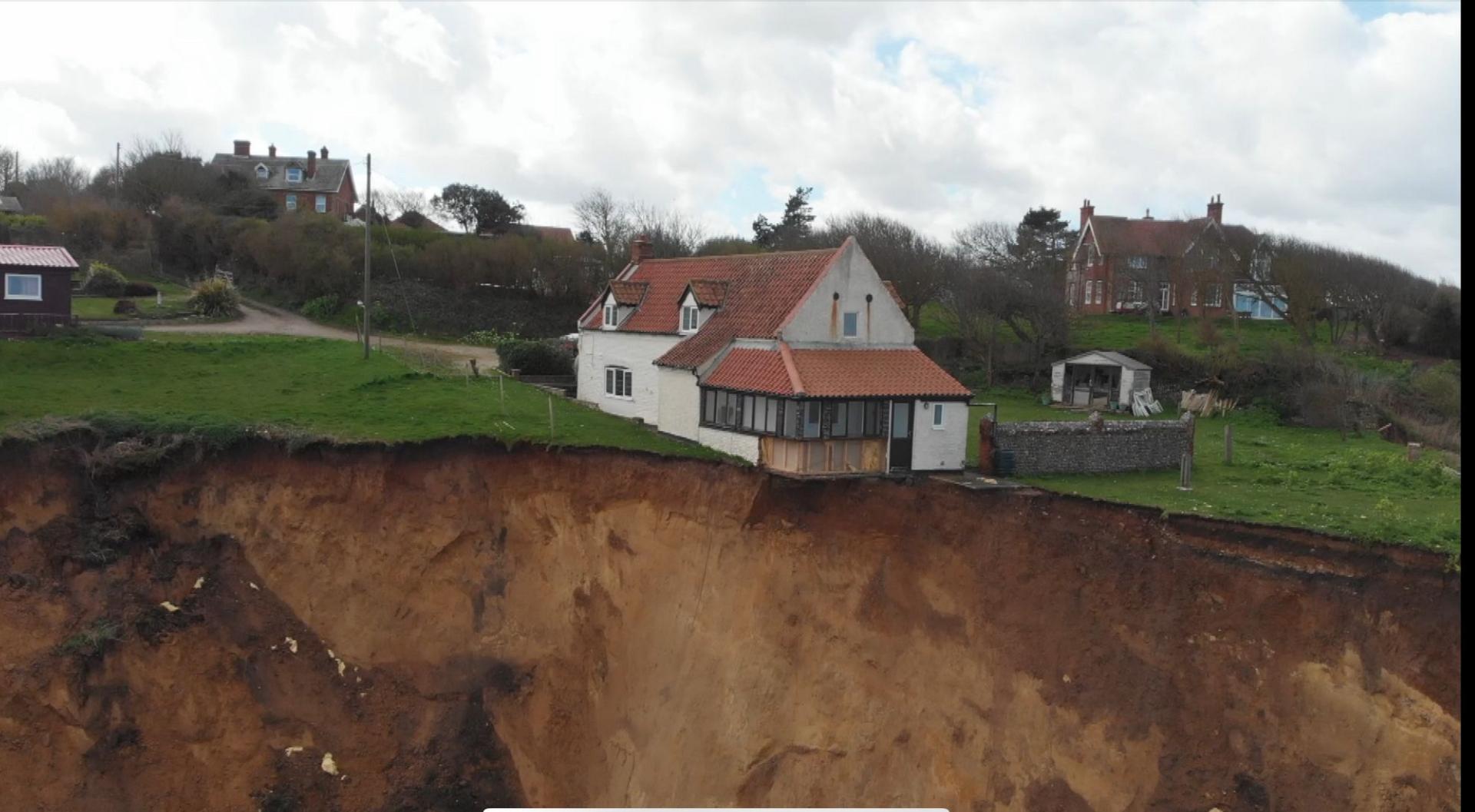 A drone image of the farmhouse partially hanging over the cliff edge