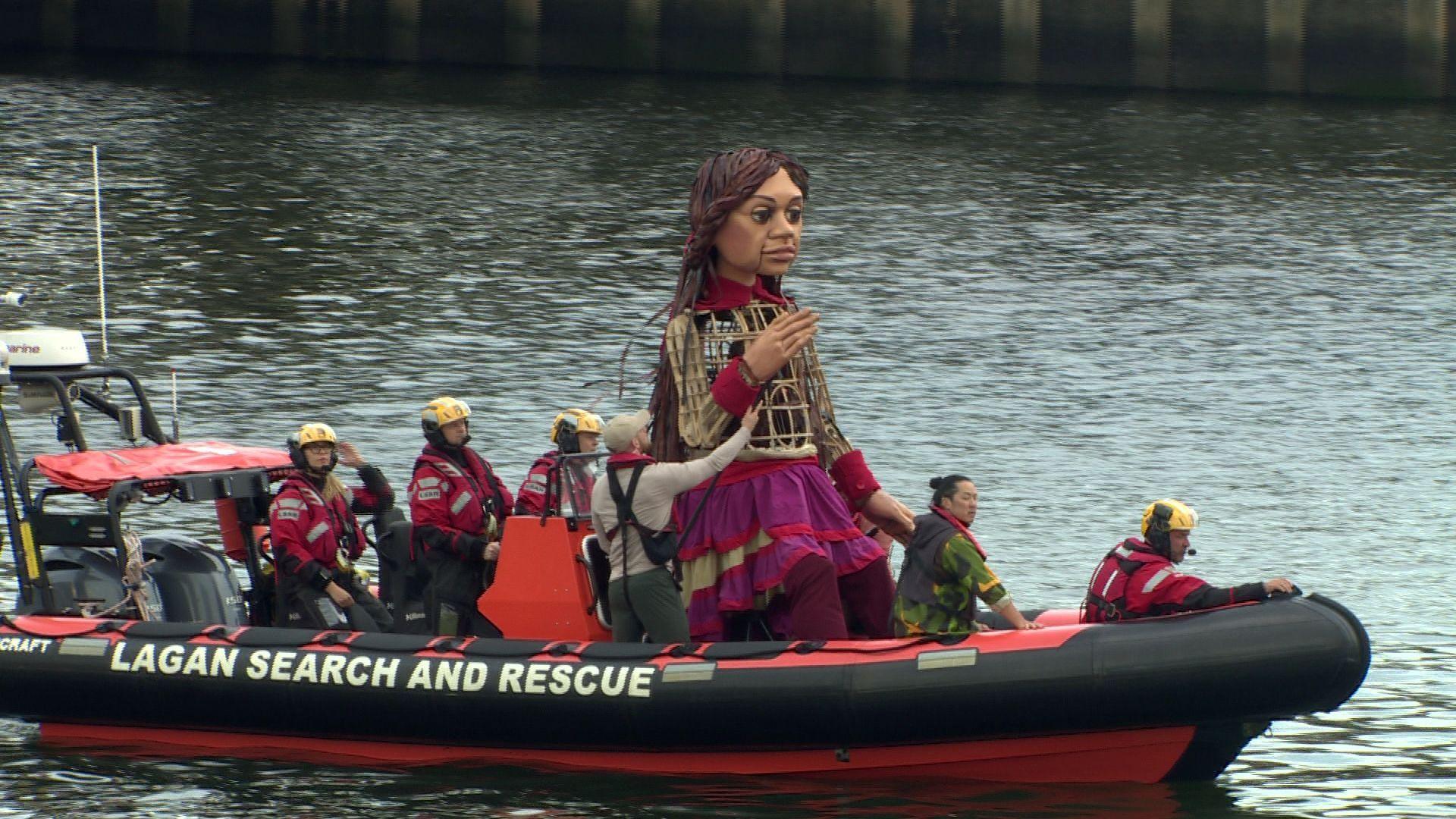 Large puppet with handlers, Little Amal on a Lagan Search and Rescue boat