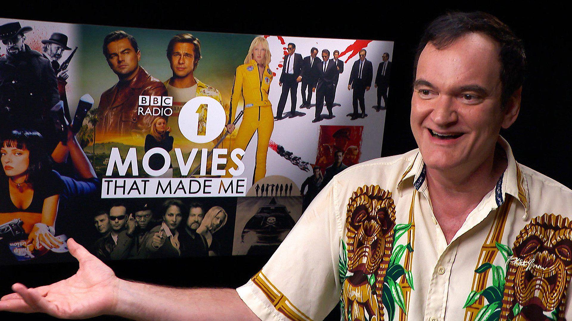 Quentin Tarantion smiling with his hand out.  A graphic with .ý Radio 1 Movies That Made Me' is behind him which has images of his films on it