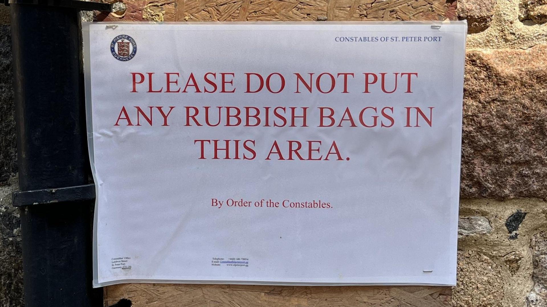 A laminated sign on a wall which reads 'Please do not put any rubbish bags in this area'