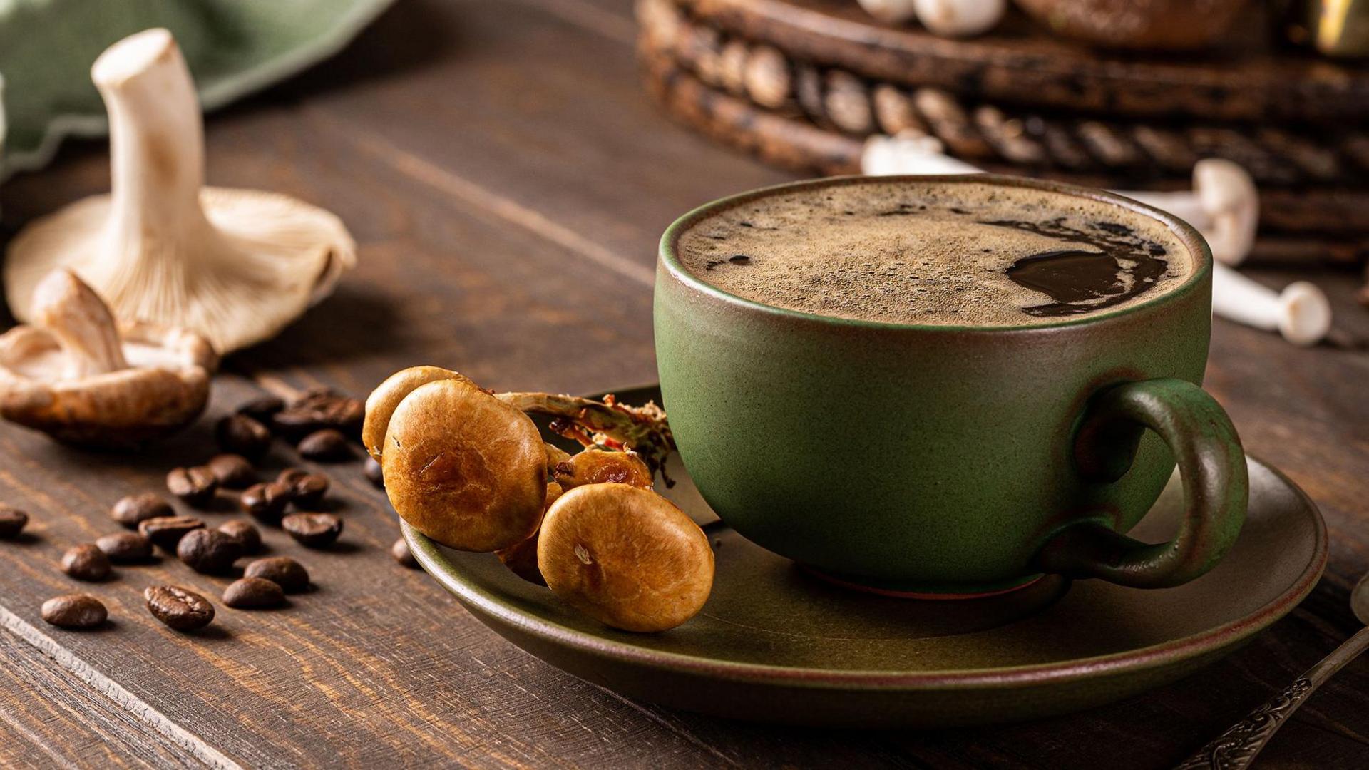 Trendy superfood mushroom coffee in green cup on wooden background. 
