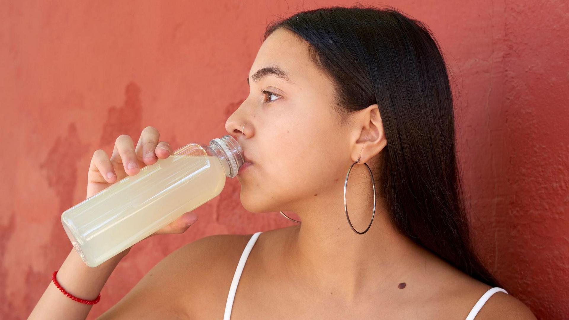 Young woman drinking a refreshing beverage from a plastic bottle 