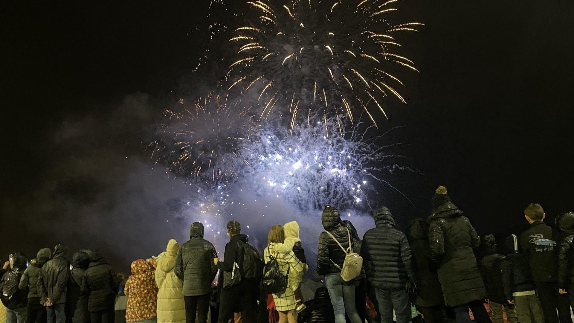 Fireworks explode while a crowd watch on