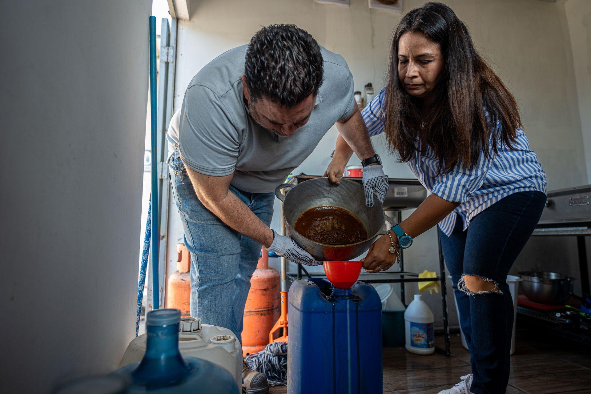 Engineer Edgardo David Guzmán and a coffee shop owner are filling her used cooking oil, that was used to fry lunch, into a canister for processing. Comayagua, 08 March 2025