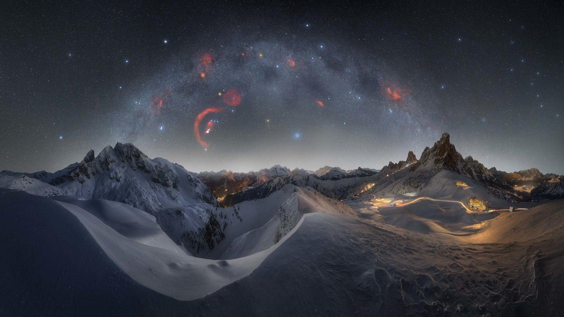 Red specks in the sky and the Milky Way above the snowy Dolomites