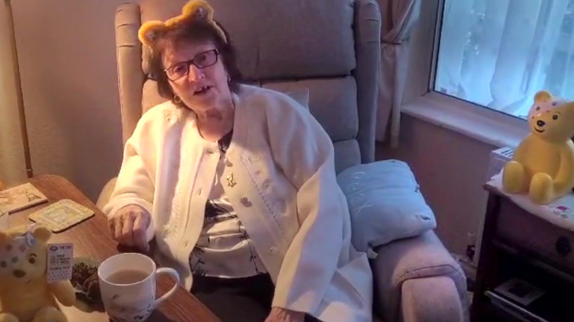 Thelma sat next to a cup of tea and a teddy bear of Pudsey